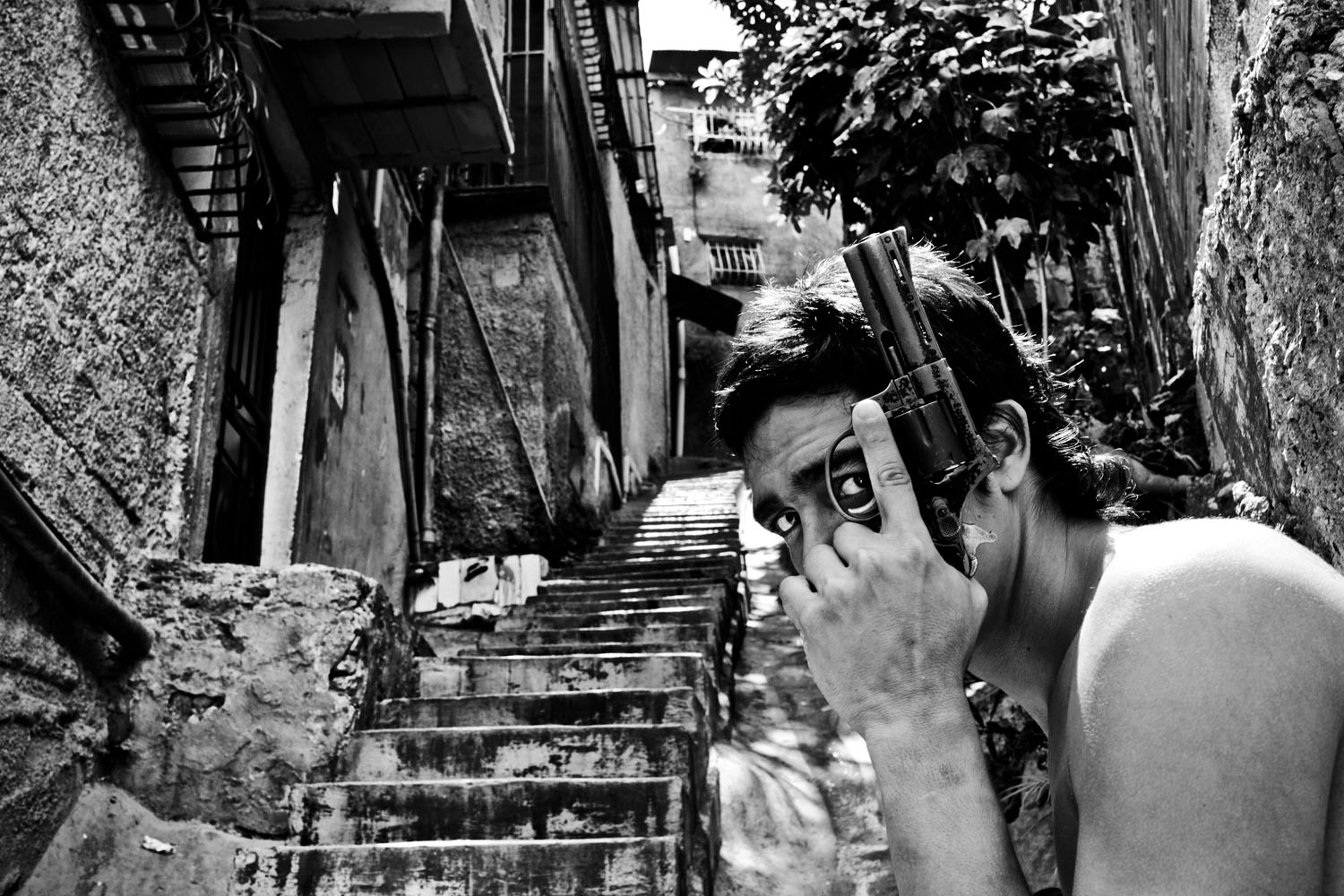 image: A gang member poses with a gun in Caracas. Some 50 homicides occur in the city each week.