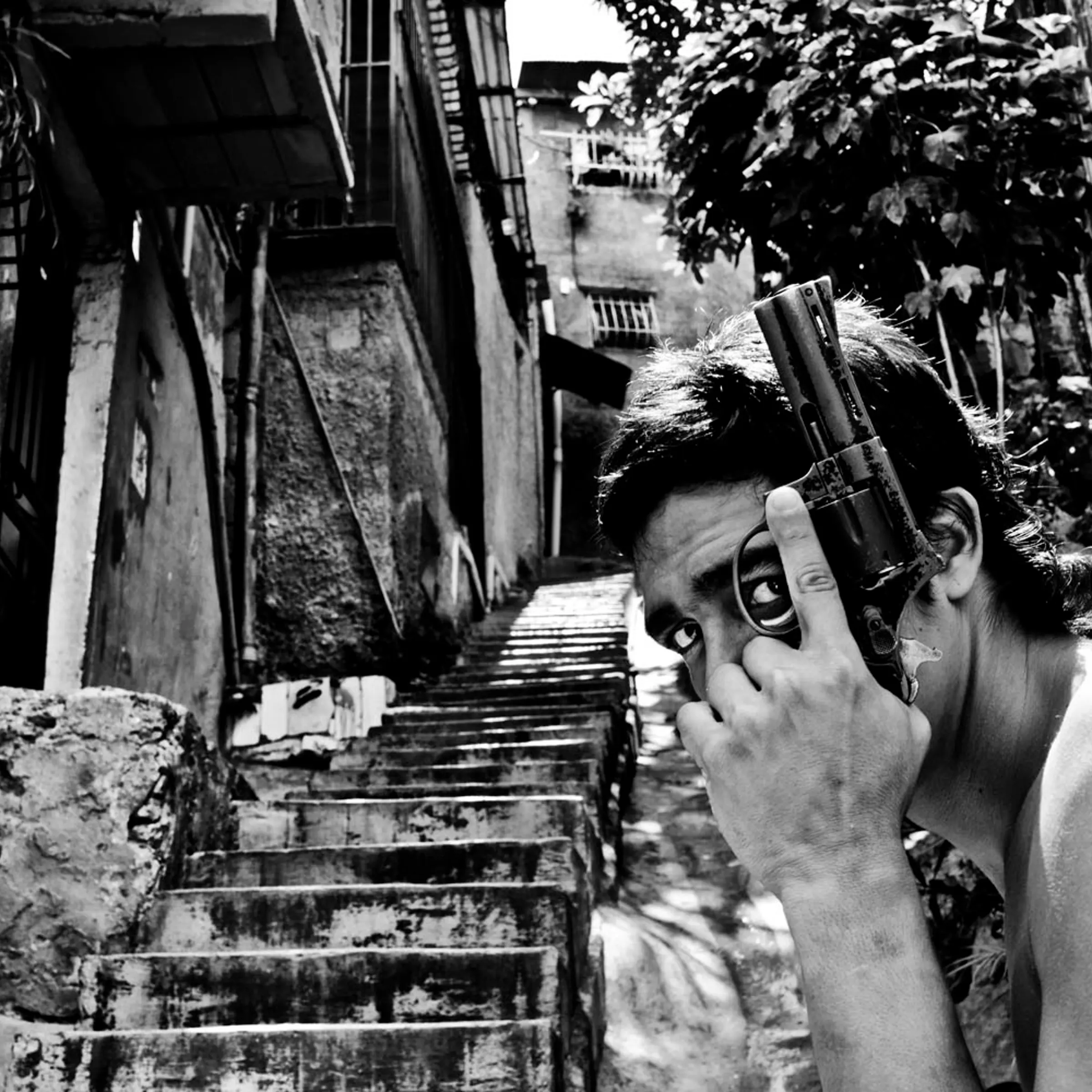 image: A gang member poses with a gun in Caracas. Some 50 homicides occur in the city each week.