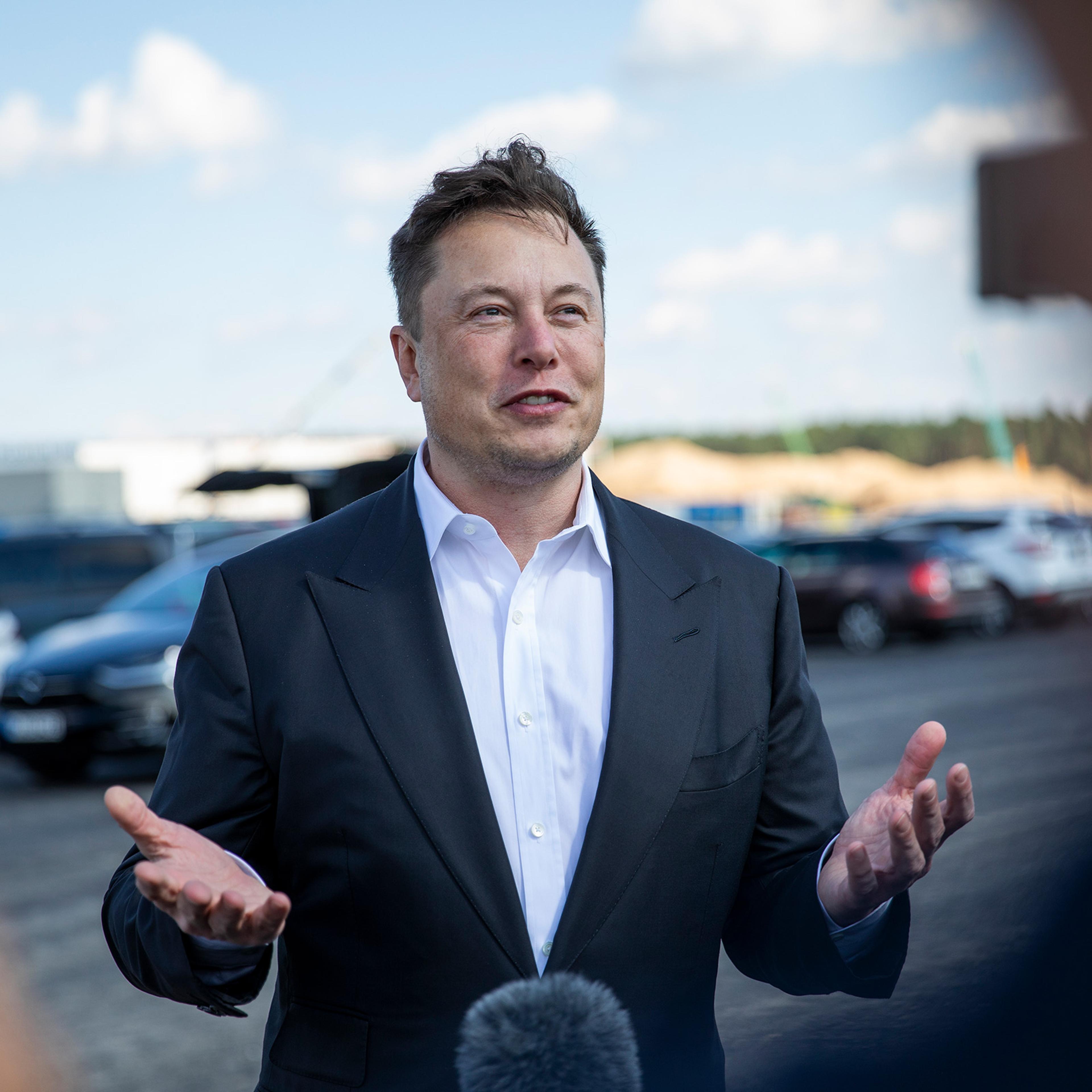 Elon Musk talks to the press as he arrives to see the construction site of the new Tesla Gigafactory near Berlin