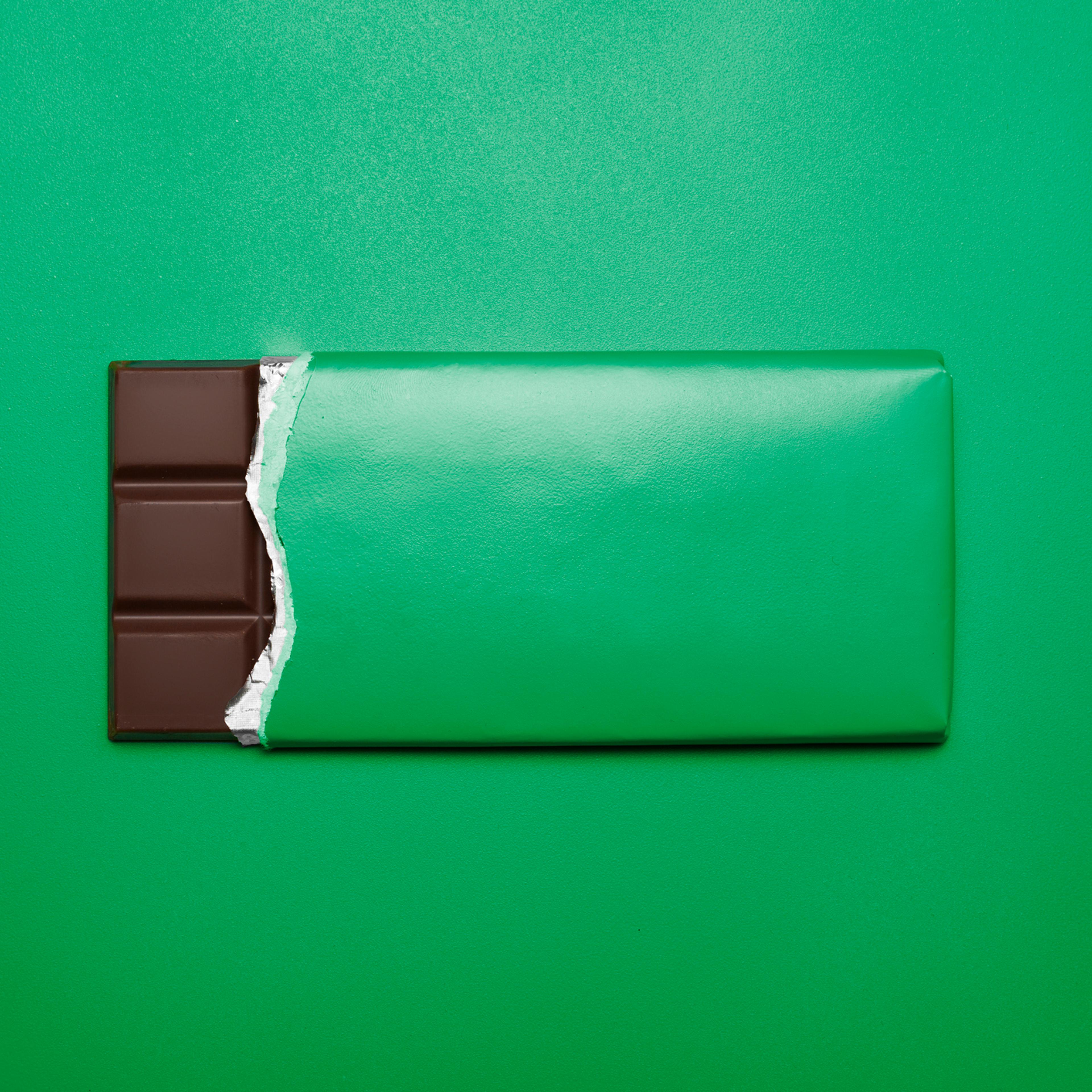 Bar of chocolate on green background