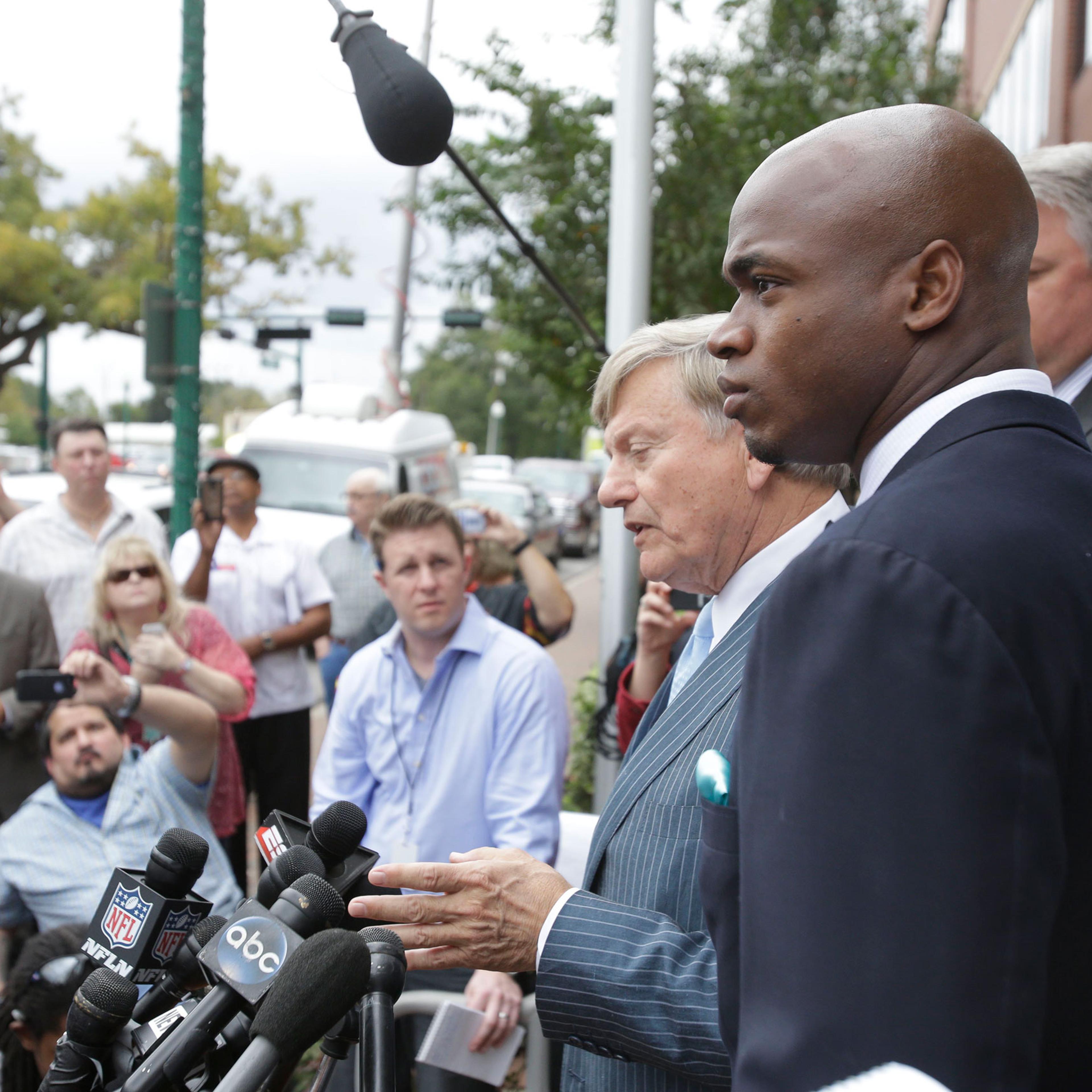 From right: Minnesota Vikings running back Adrian Peterson and his attorney Rusty Hardin speak to the media after pleading no contest to an assault charge on Nov. 4, 2014, in Conroe, Tx.