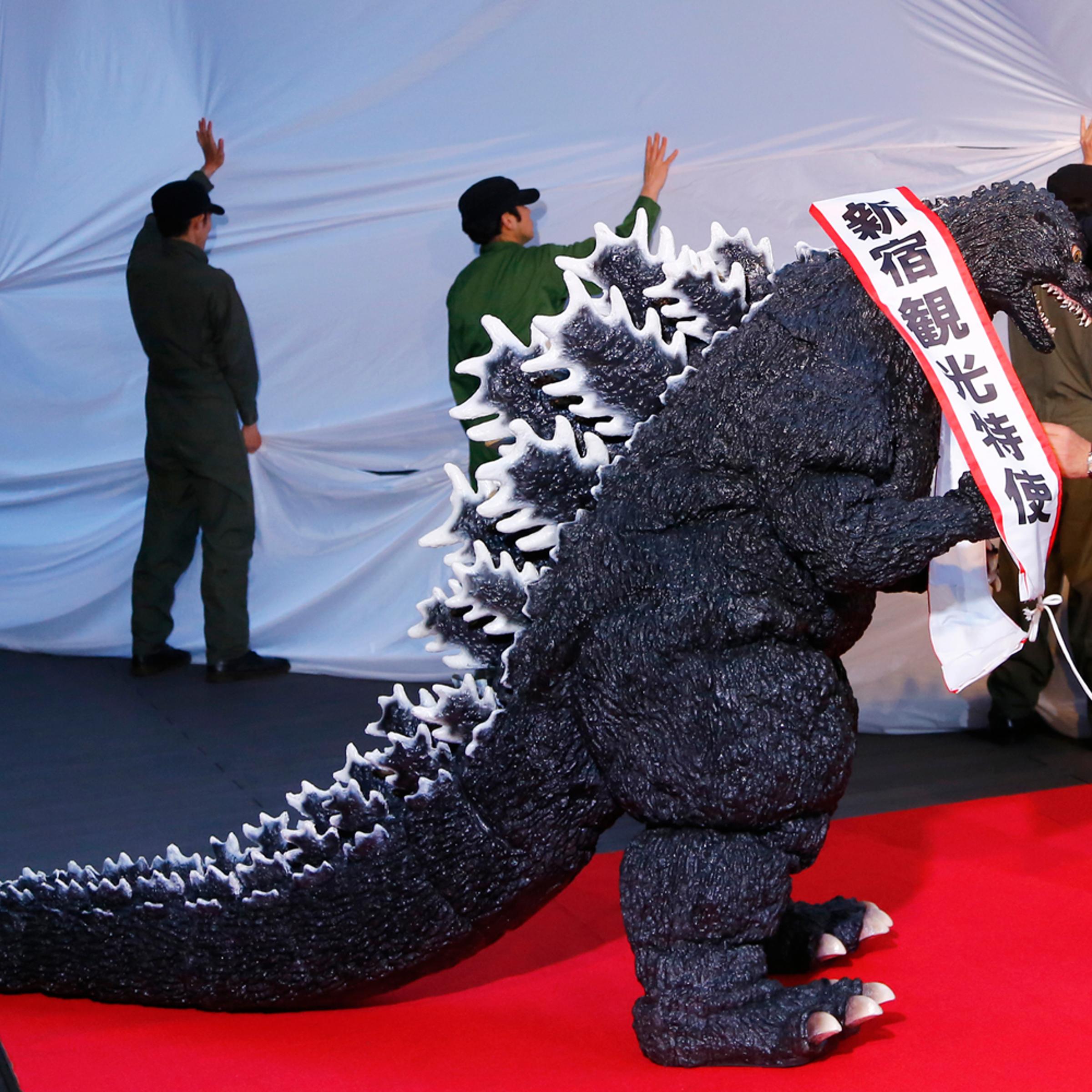 Godzilla gets a sash of "Shinjuku-ward tourism ambassador" from the Kabuki-cho Shopping Area Promotion Association Chief Director Mototsugu Katagiri of Tokyo's Shinjuku-ward during its awards ceremony in Tokyo, April 9, 2015.