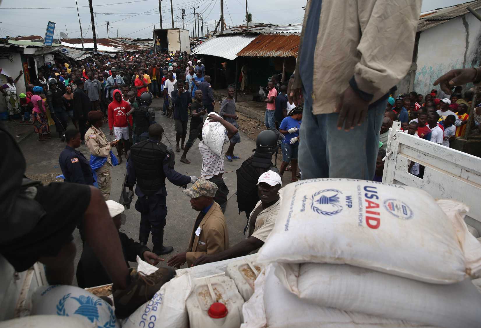 Residents of the West Point slum receive food aid during the second day of the government's Ebola quarantine on their neighborhood on August 21, 2014 in Monrovia, Liberia.