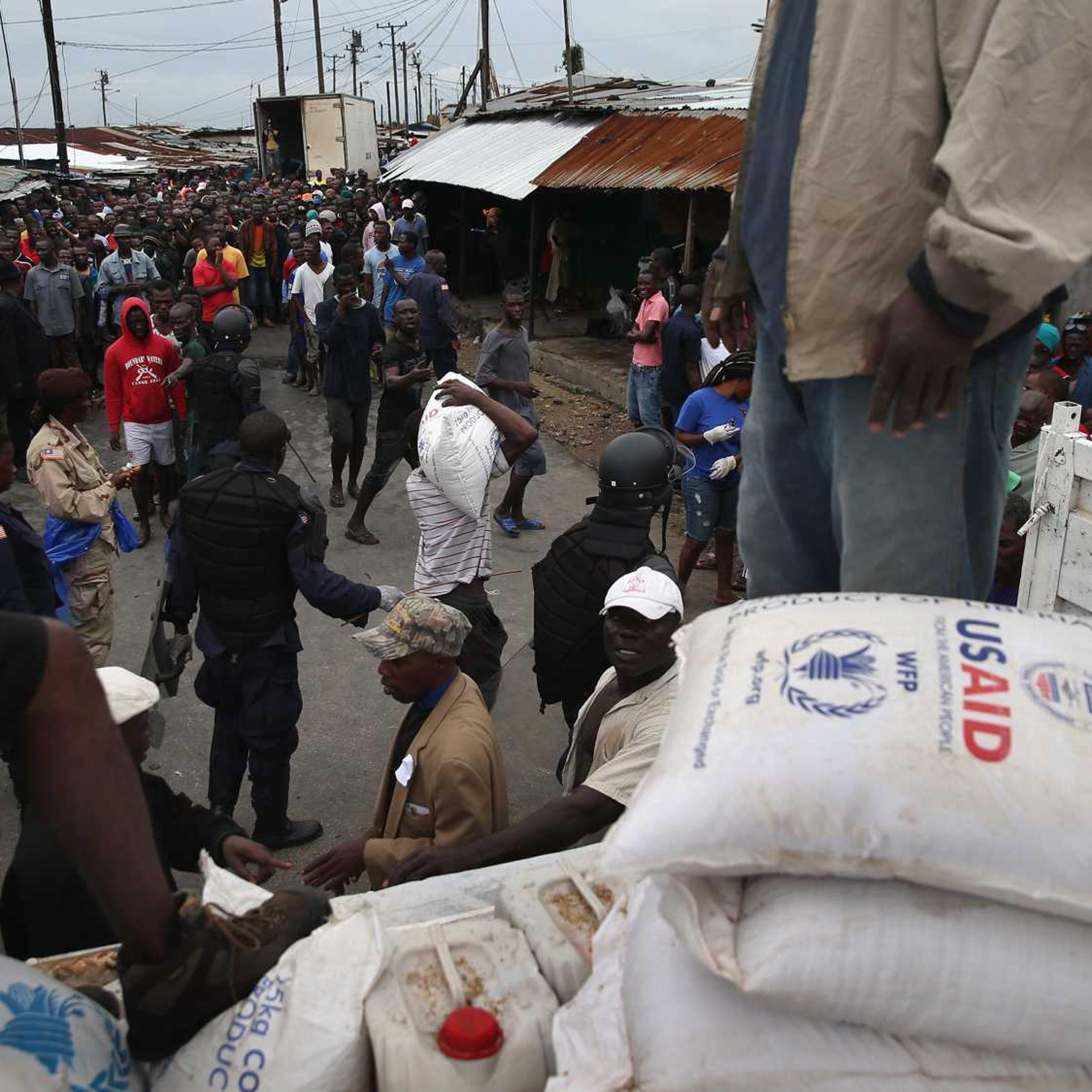 Residents of the West Point slum receive food aid during the second day of the government's Ebola quarantine on their neighborhood on August 21, 2014 in Monrovia, Liberia.