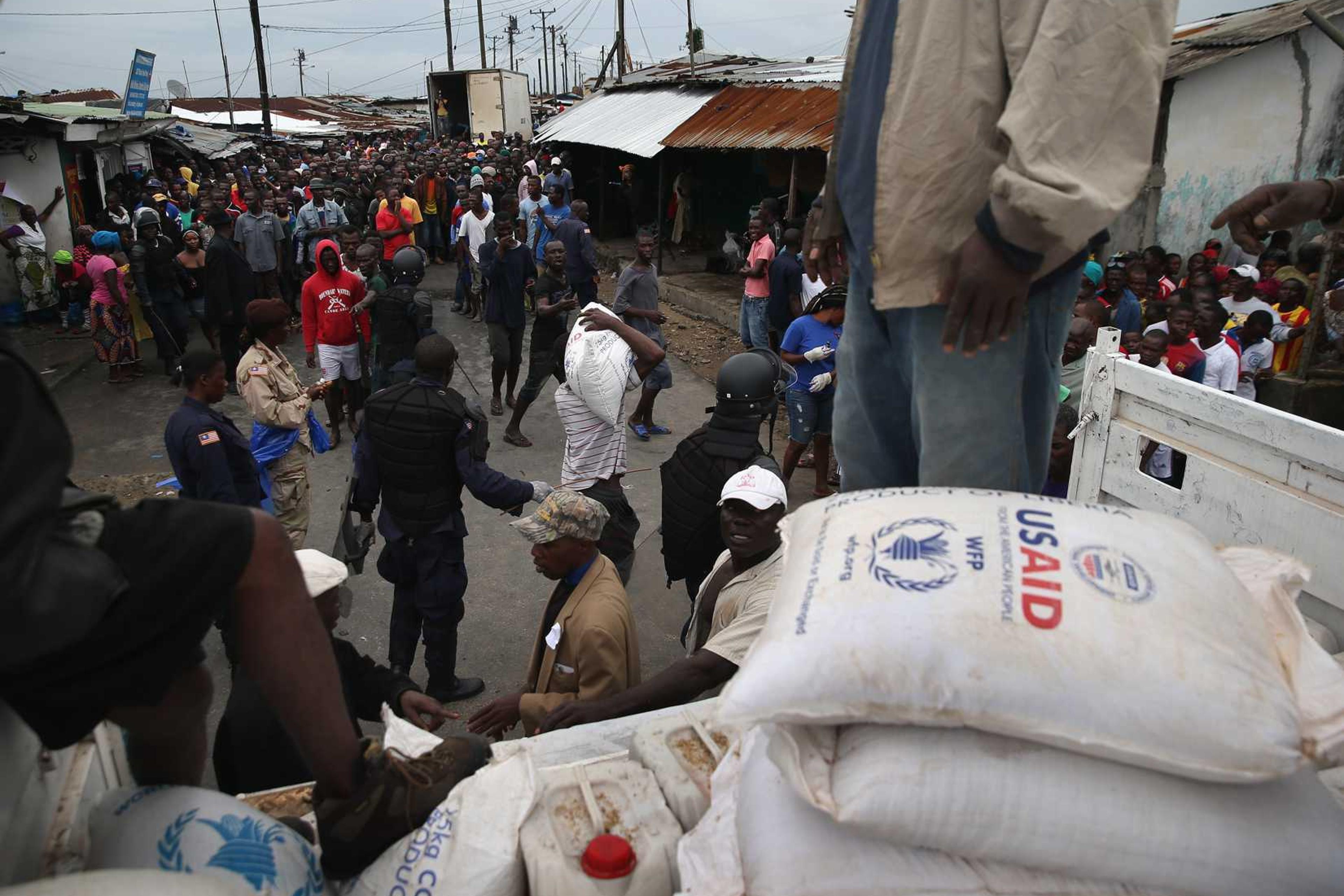 Residents of the West Point slum receive food aid during the second day of the government's Ebola quarantine on their neighborhood on August 21, 2014 in Monrovia, Liberia.