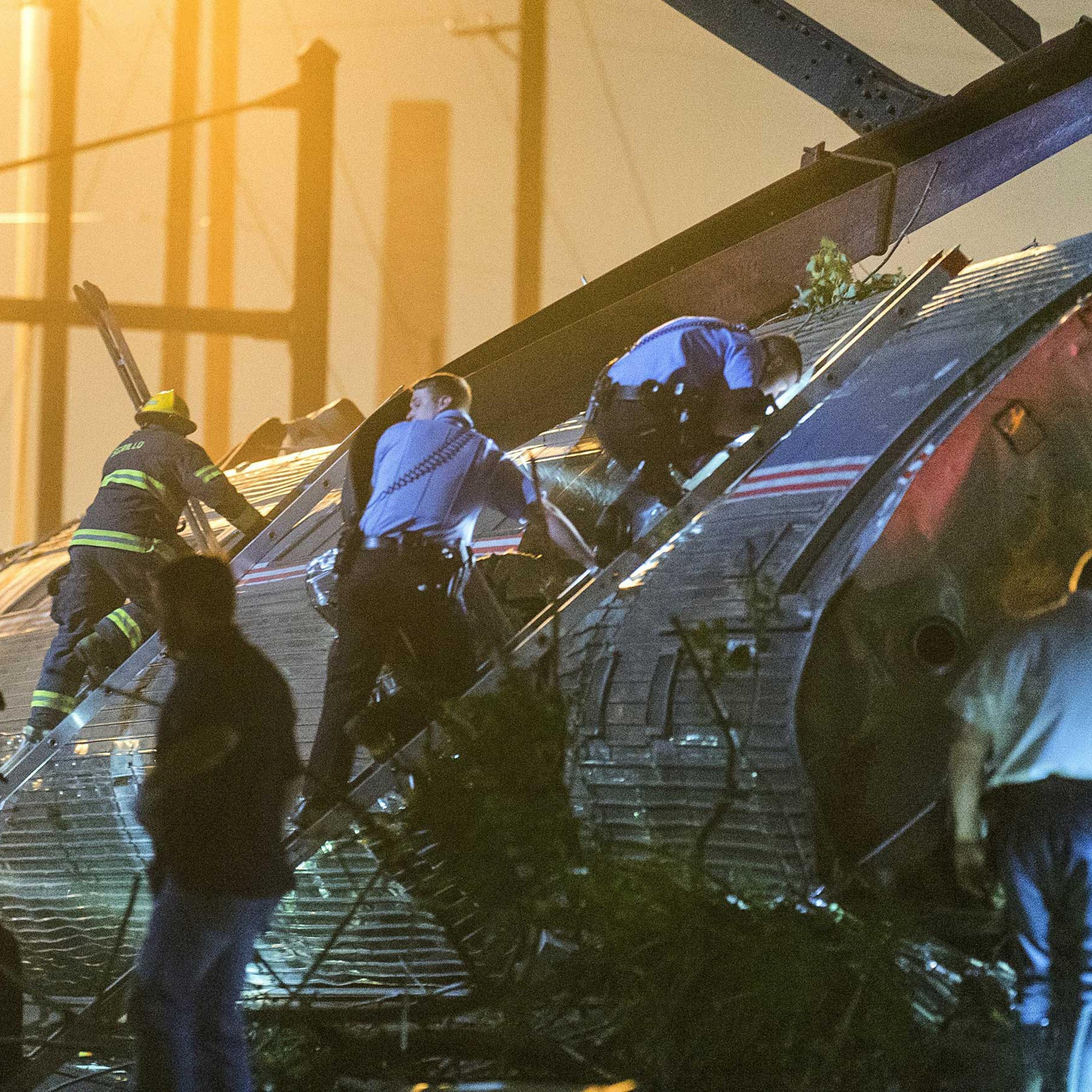 Rescue workers climb into the wreckage of a derailed Amtrak train to search for victims in Philadelphia on May 12, 2015.