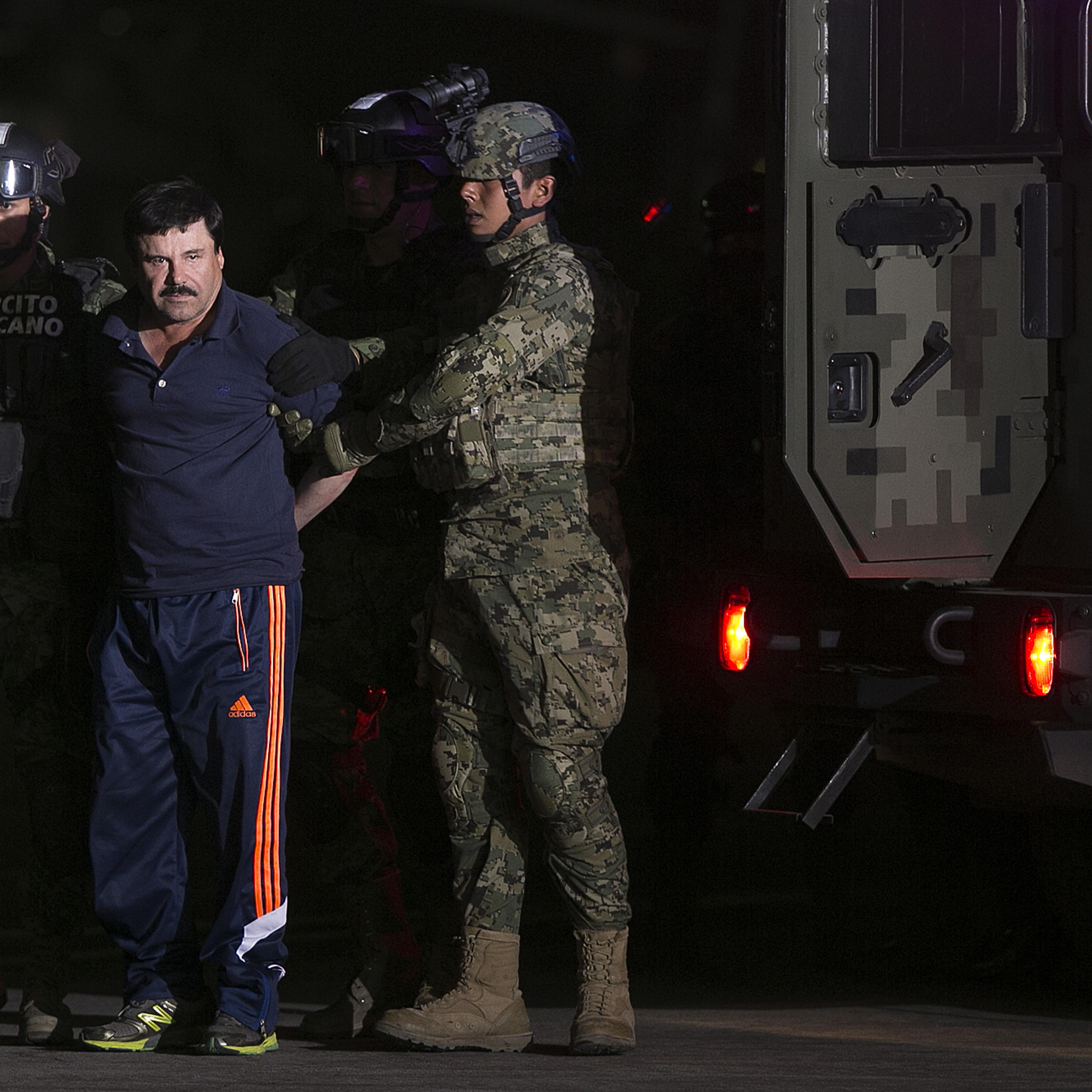 Joaquin Guzman, the world's most wanted-drug trafficker, second left, is escorted by Mexican security forces at a Navy hangar in Mexico City, Mexico, on Jan. 8, 2016.