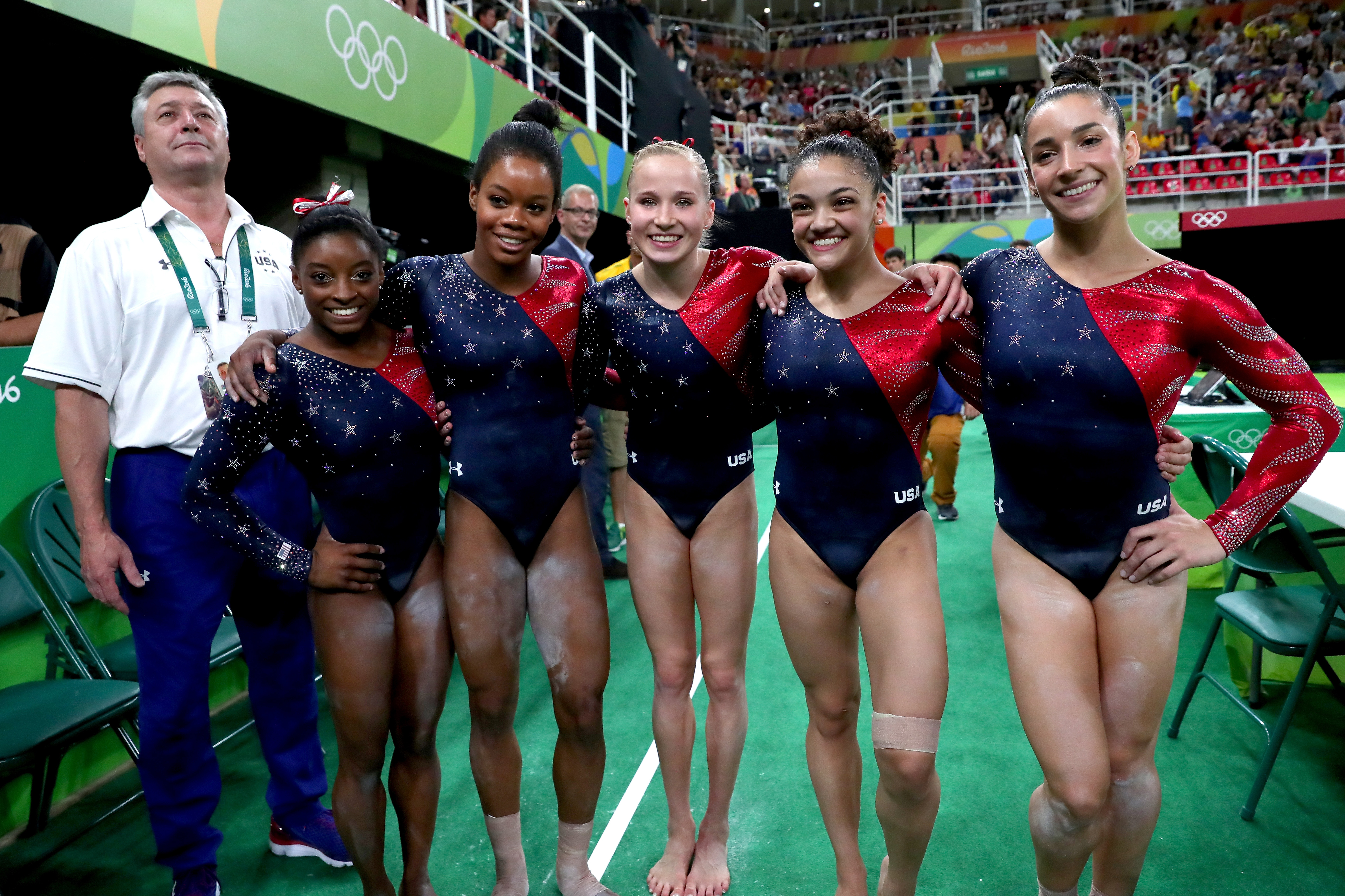 (L to R) Coach Mihai Brestyan, Simone Biles, Gabrielle Douglas, Madison Kocian, Lauren Hernandez and Alexandra Raisman of the United States pose for photographs after Women's qualification for Artistic Gymnastics on Day 2 of the Rio 2016 Olympic Games at