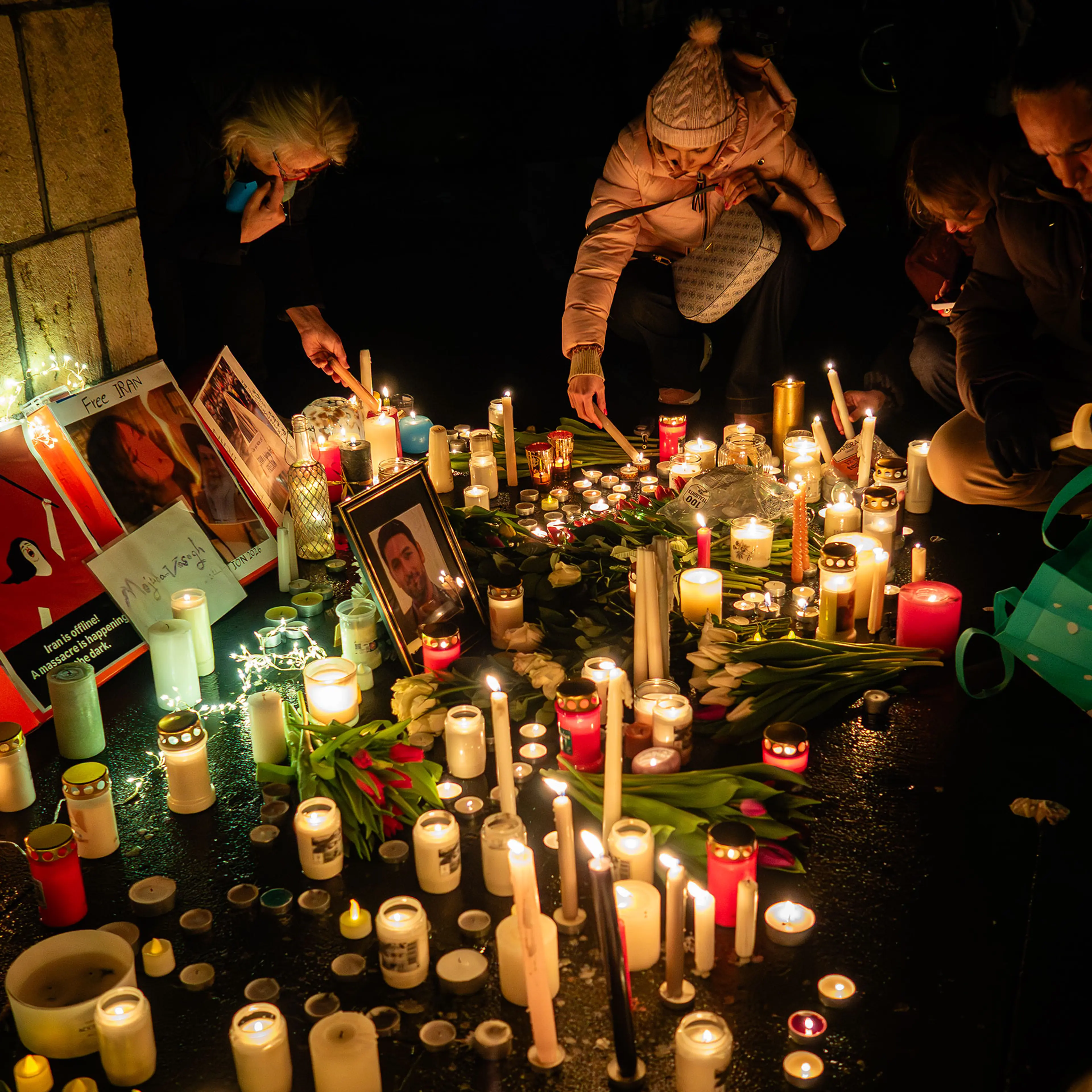People are seen lighting candles as attendees gather at