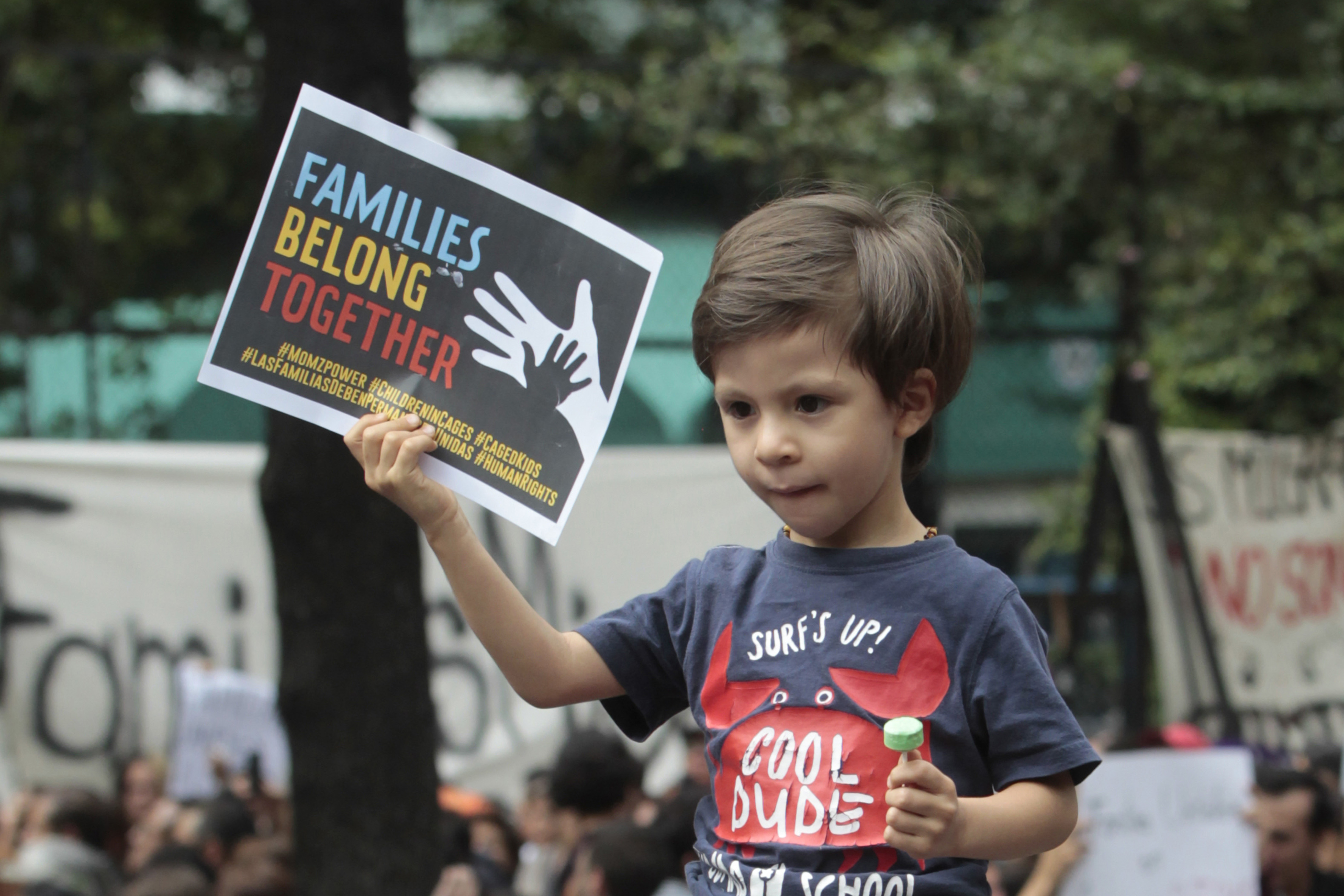 Boy carries sign saying "Families Belong Together" at Mexico City protest
