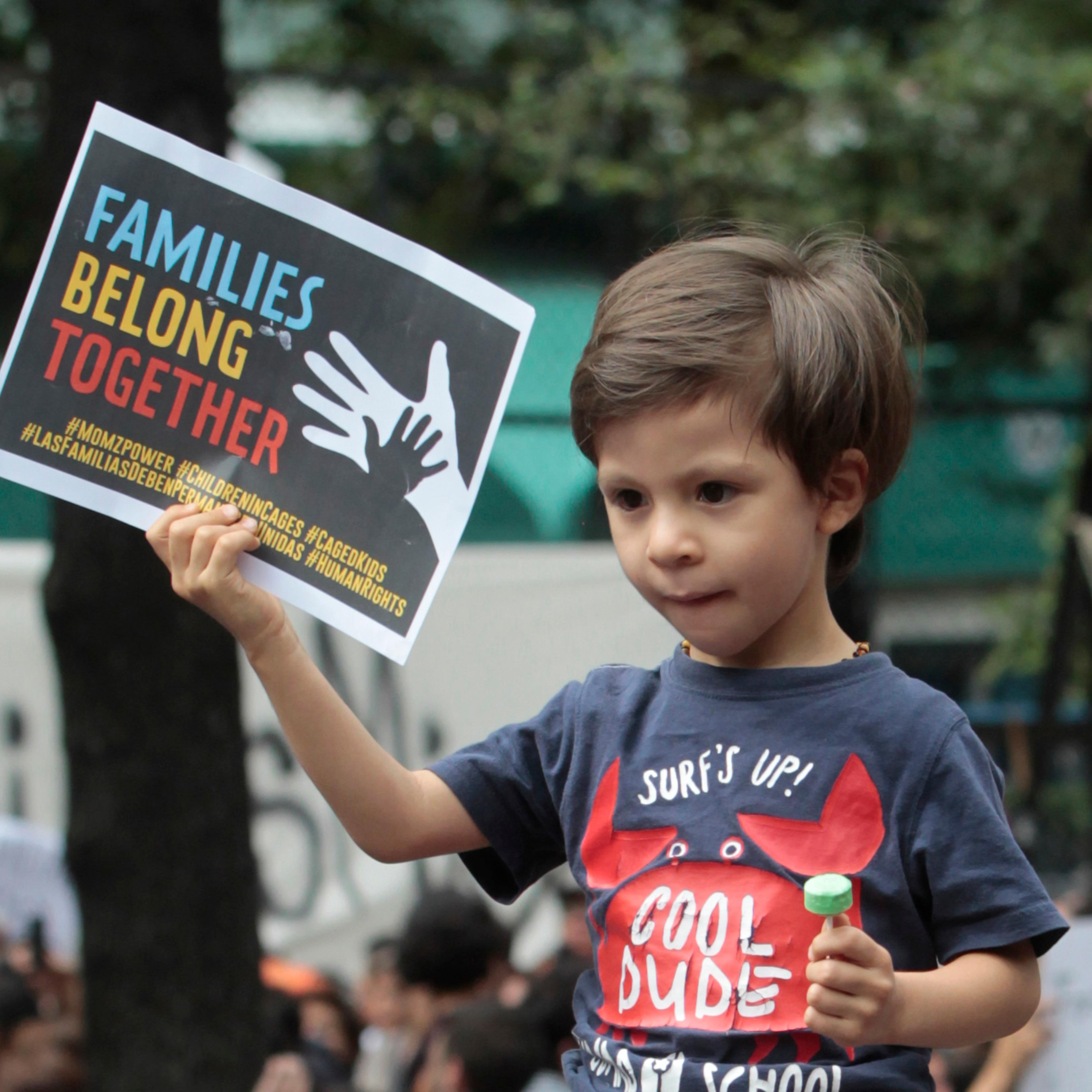Boy carries sign saying "Families Belong Together" at Mexico City protest
