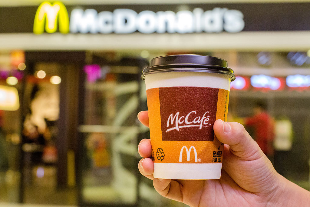 A customer holds a cup of Coffee served by McCafe