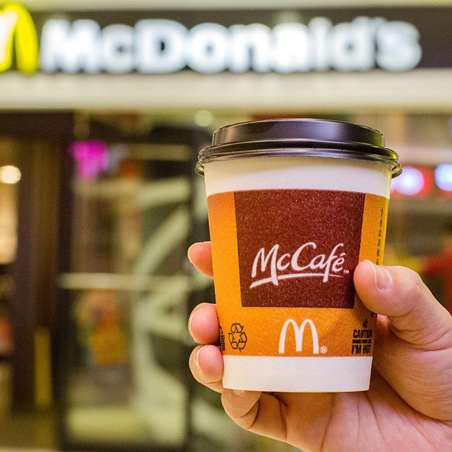 A customer holds a cup of Coffee served by McCafe