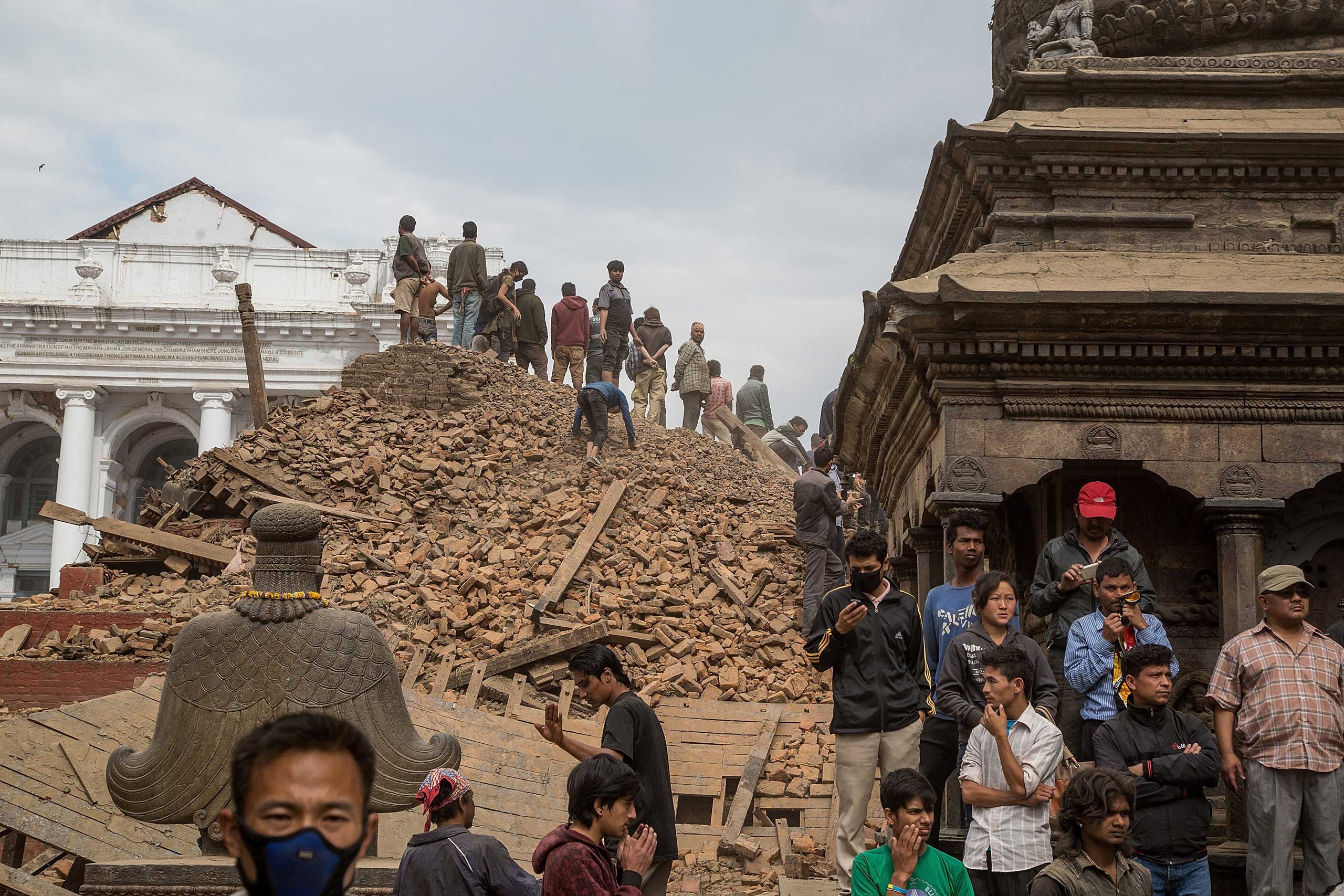 Emergency workers and bystanders clear debris while searching for survivors under a collapsed temple in Basantapur Durbar Square following an earthquake in Kathmandu on April 25, 2015.