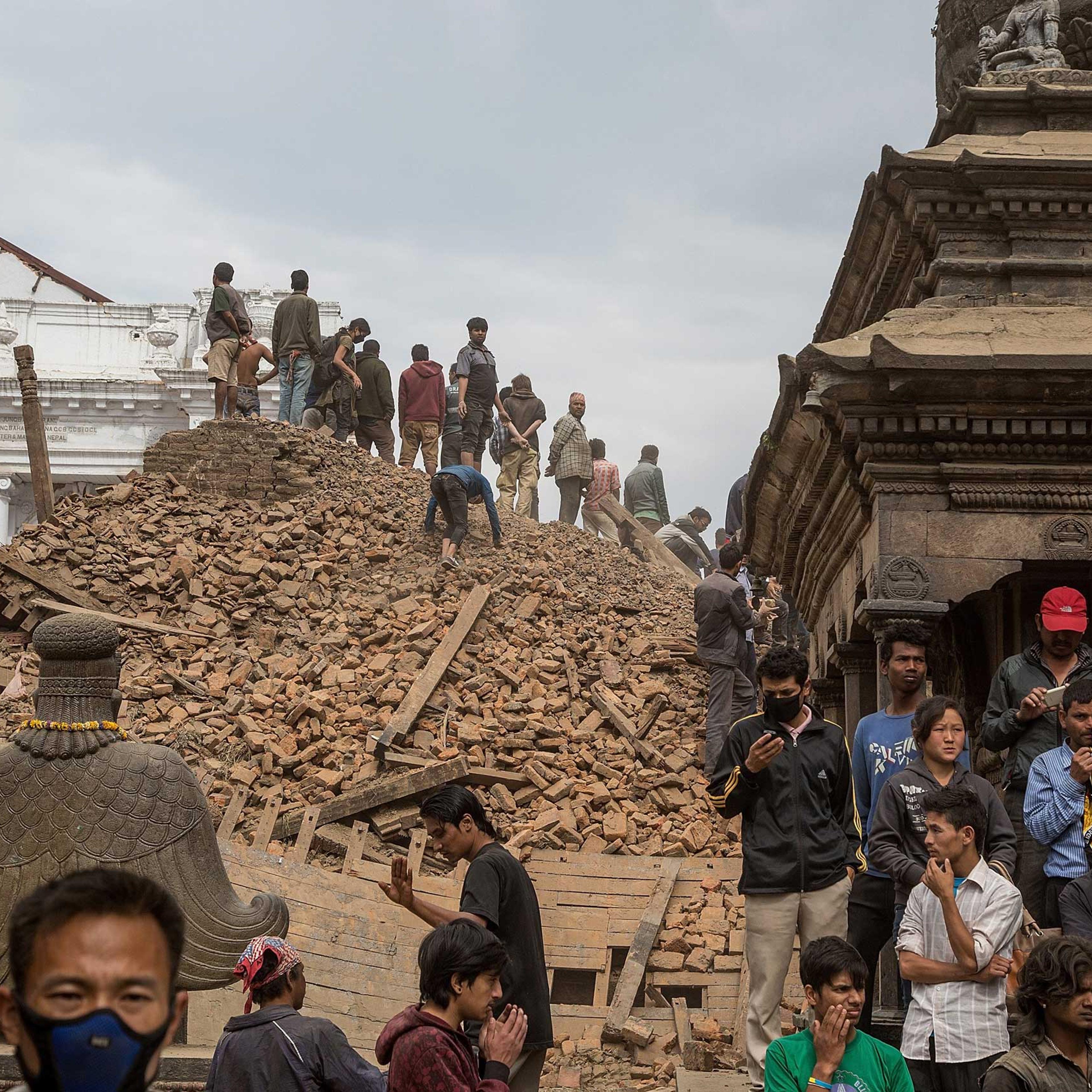 Emergency workers and bystanders clear debris while searching for survivors under a collapsed temple in Basantapur Durbar Square following an earthquake in Kathmandu on April 25, 2015.