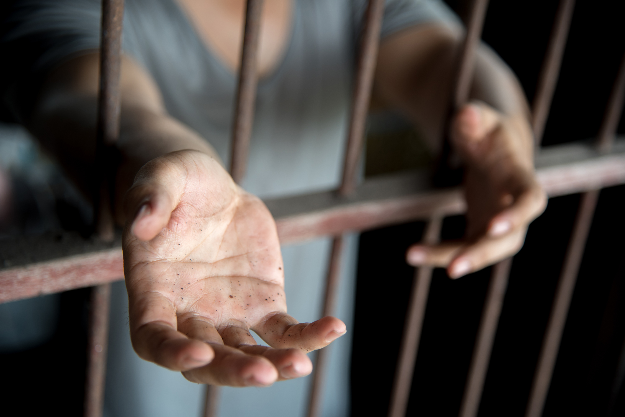 hands reaching out of a jail cell
