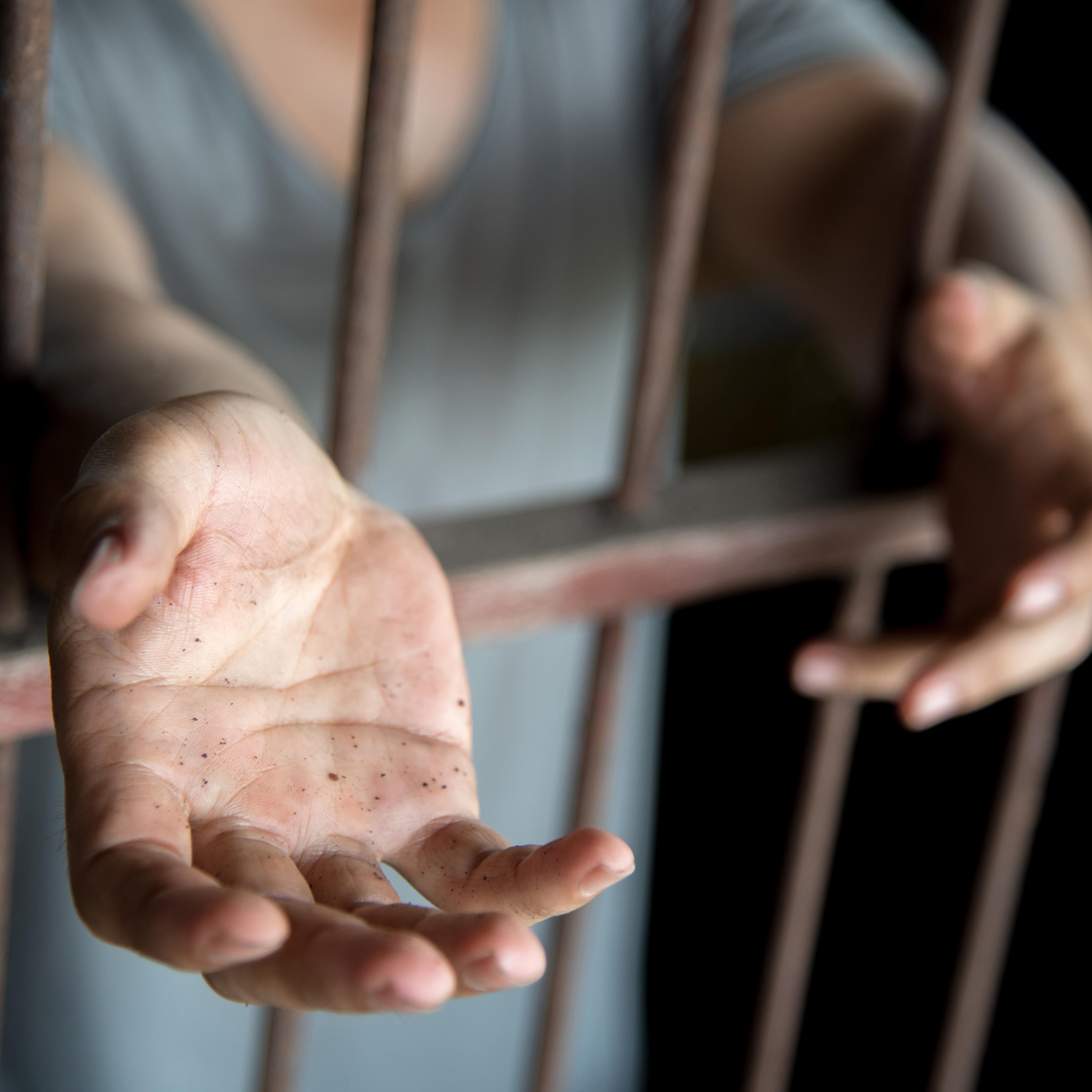 hands reaching out of a jail cell