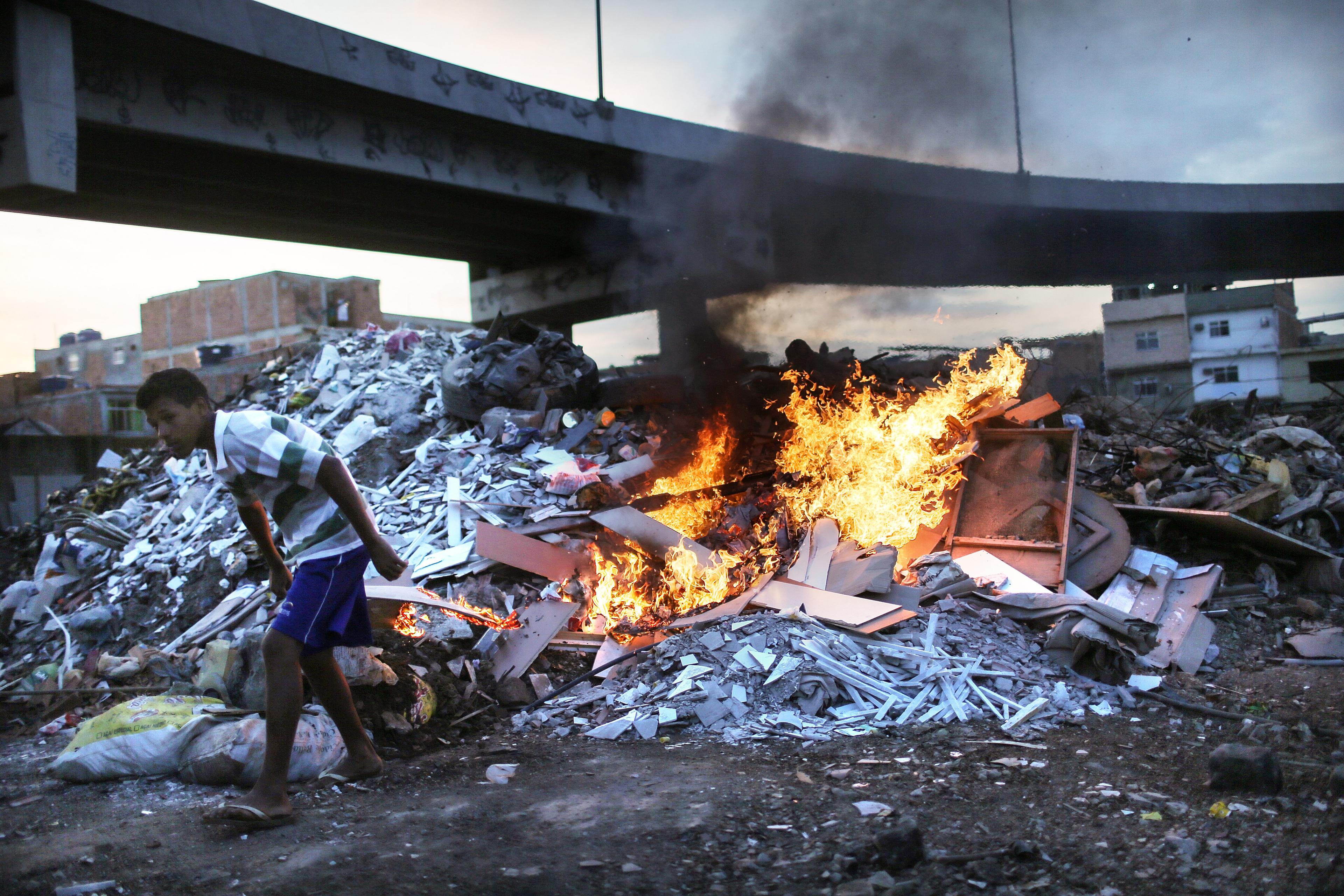 Trash is burned in an area where garbage is dumped near the main highway linking Rio's international airport to the city in the Mare favela community complex in Rio de Janeiro on July 18, 2016.