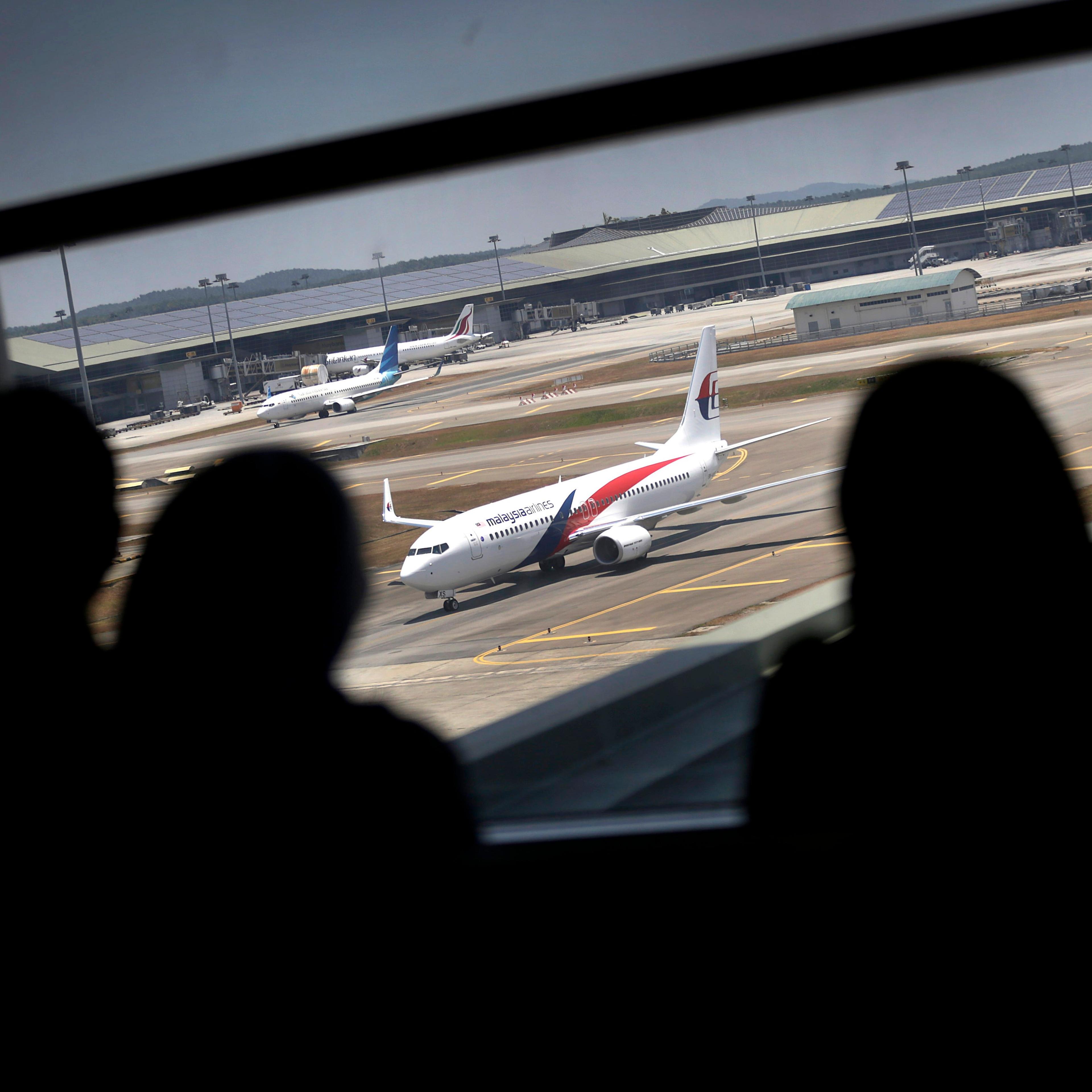 Women are silhouetted as they watch a Malaysia Airlines jet taxi on the tarmac at the Kuala Lumpur International Airport.