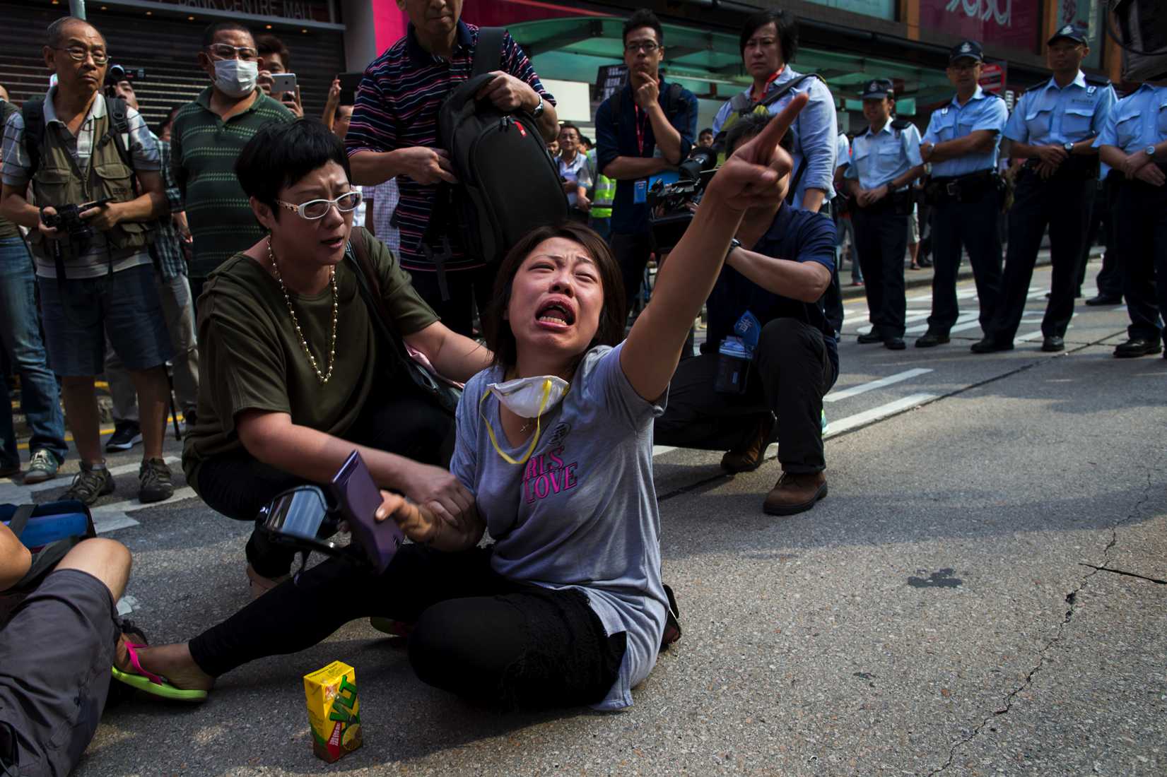 A pro-democracy protester cries in front of a line of policemen on a blocked road, after police removed barricades at Mongkok shopping district in Hong Kong October 17, 2014.