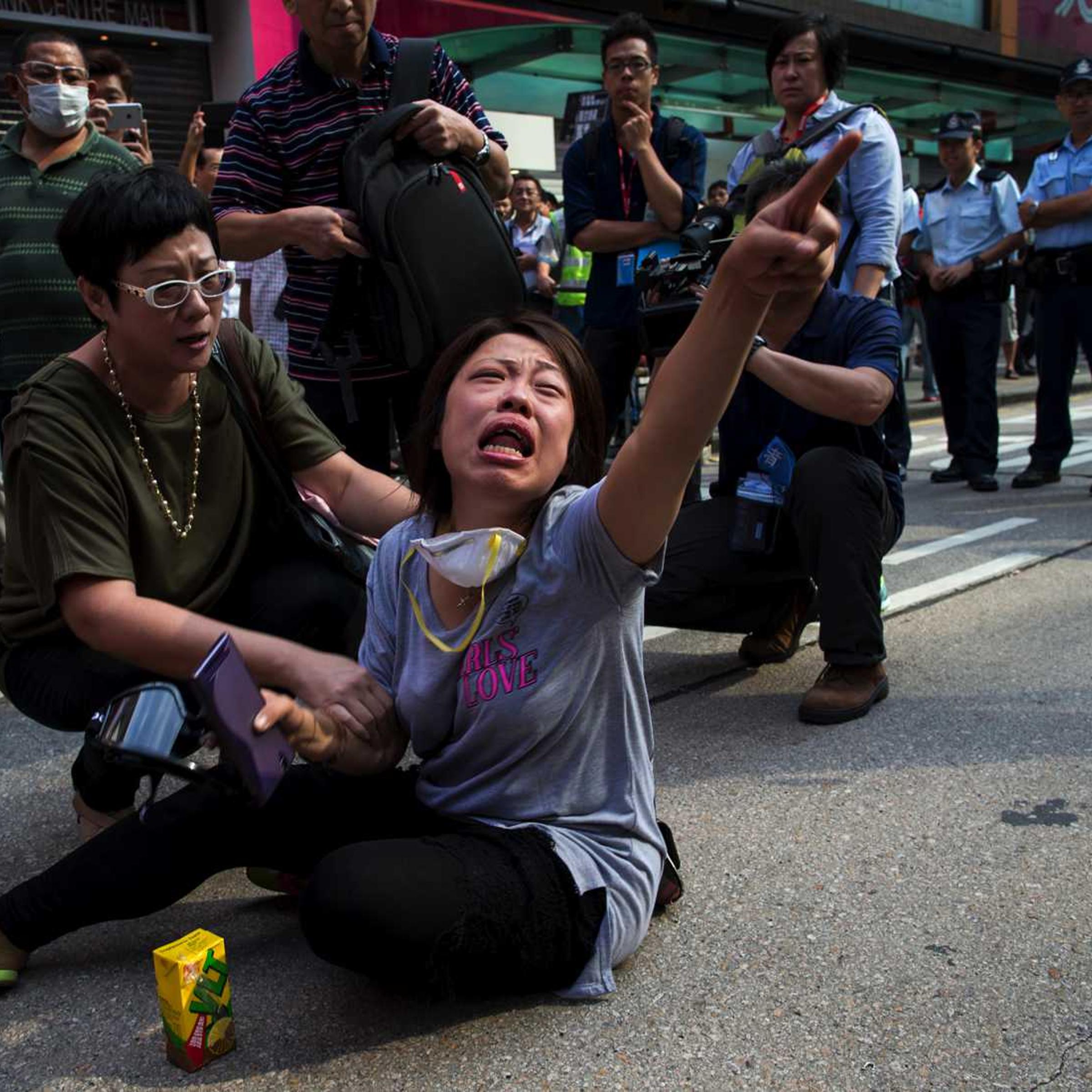 A pro-democracy protester cries in front of a line of policemen on a blocked road, after police removed barricades at Mongkok shopping district in Hong Kong October 17, 2014.