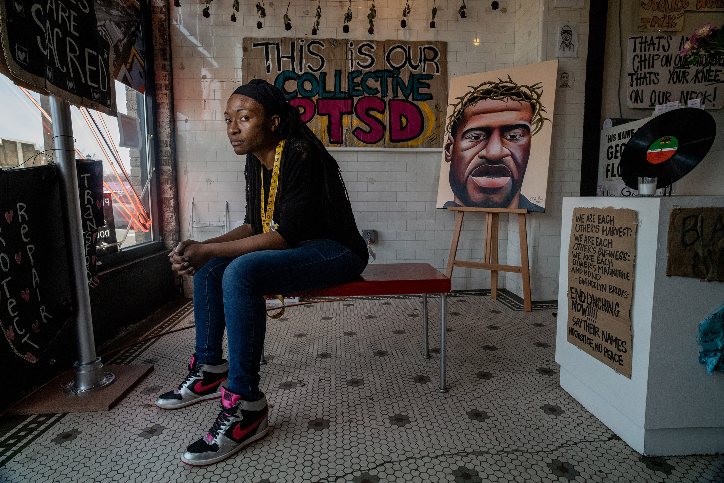 Jeanelle Austin seated here brought together a group of caretakers who maintain a memorial for George Floyd that continues to growe in Geoprge Floyd Square near the spot where he was killed.Items such as art protest signsd, candles, books and other mater