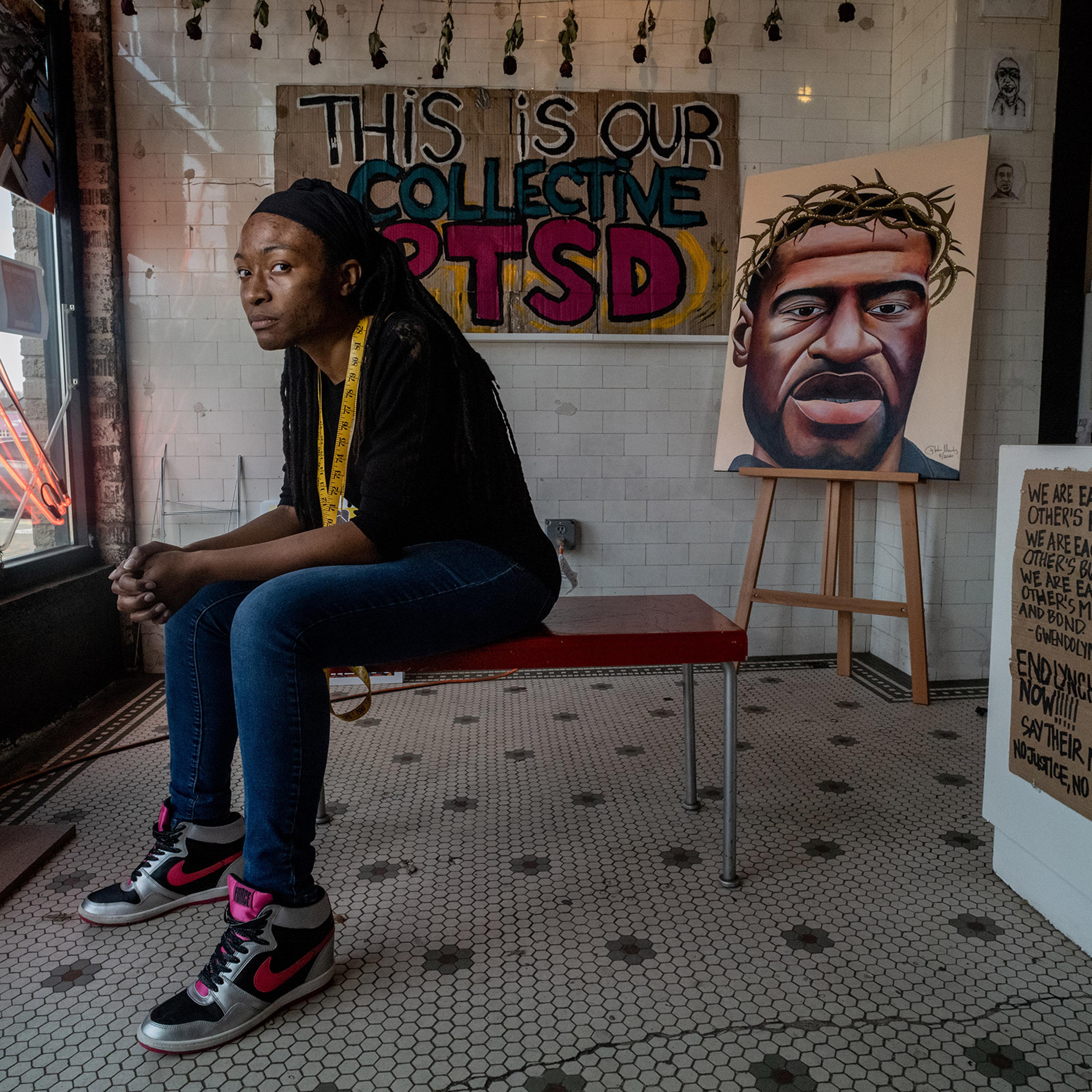 Jeanelle Austin seated here brought together a group of caretakers who maintain a memorial for George Floyd that continues to growe in Geoprge Floyd Square near the spot where he was killed.Items such as art protest signsd, candles, books and other mater