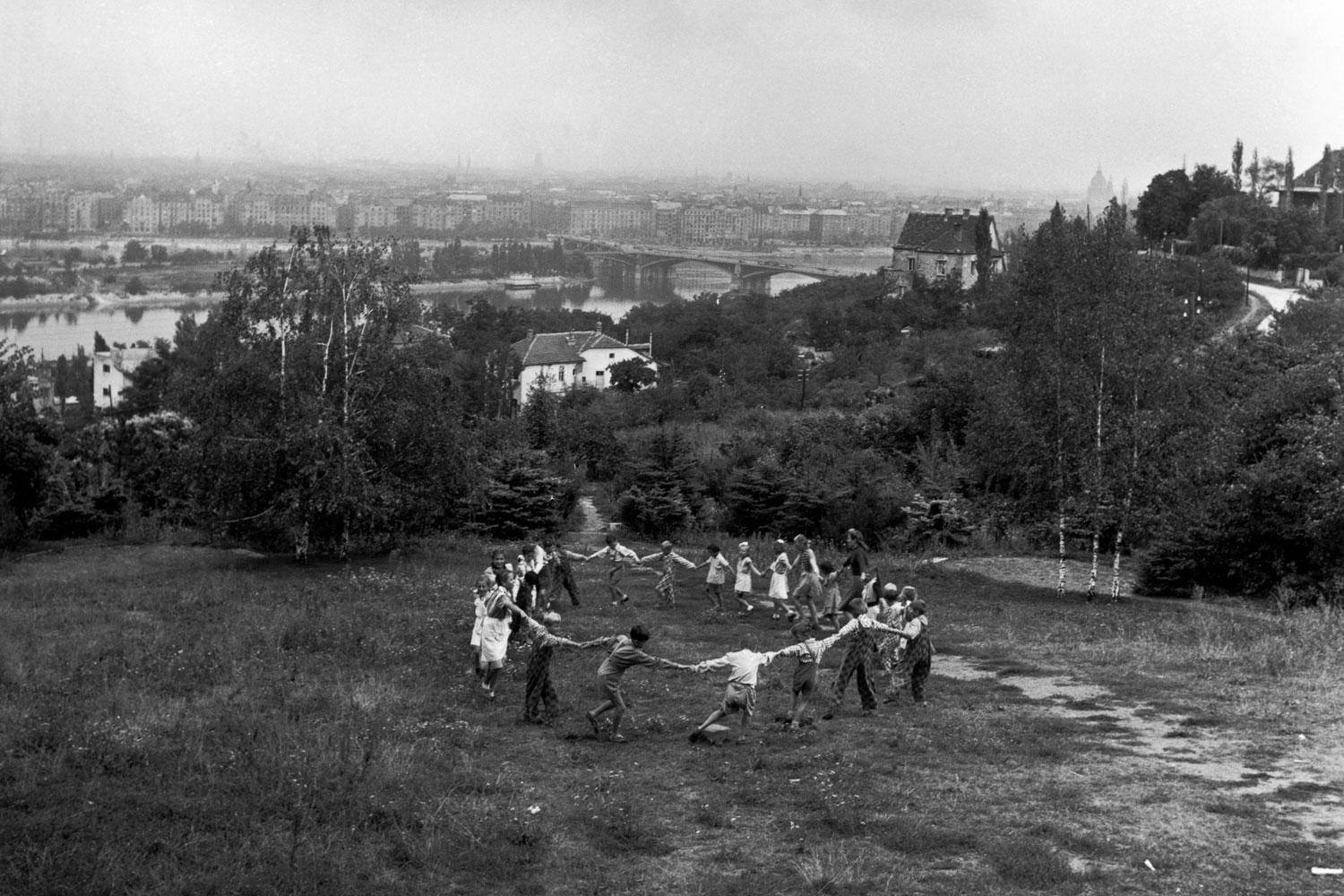 Children playing in a suburban park. Behind lies the Danube with the newly built Margareten Bridge. The theme of Ring a Ring o’ Roses, often contrasting with a ruined landscape, is recurrent in Chim’s work as well in his colleague Werner Bischof’s post-World War II European work. Budapest, Hungary. 1948.
