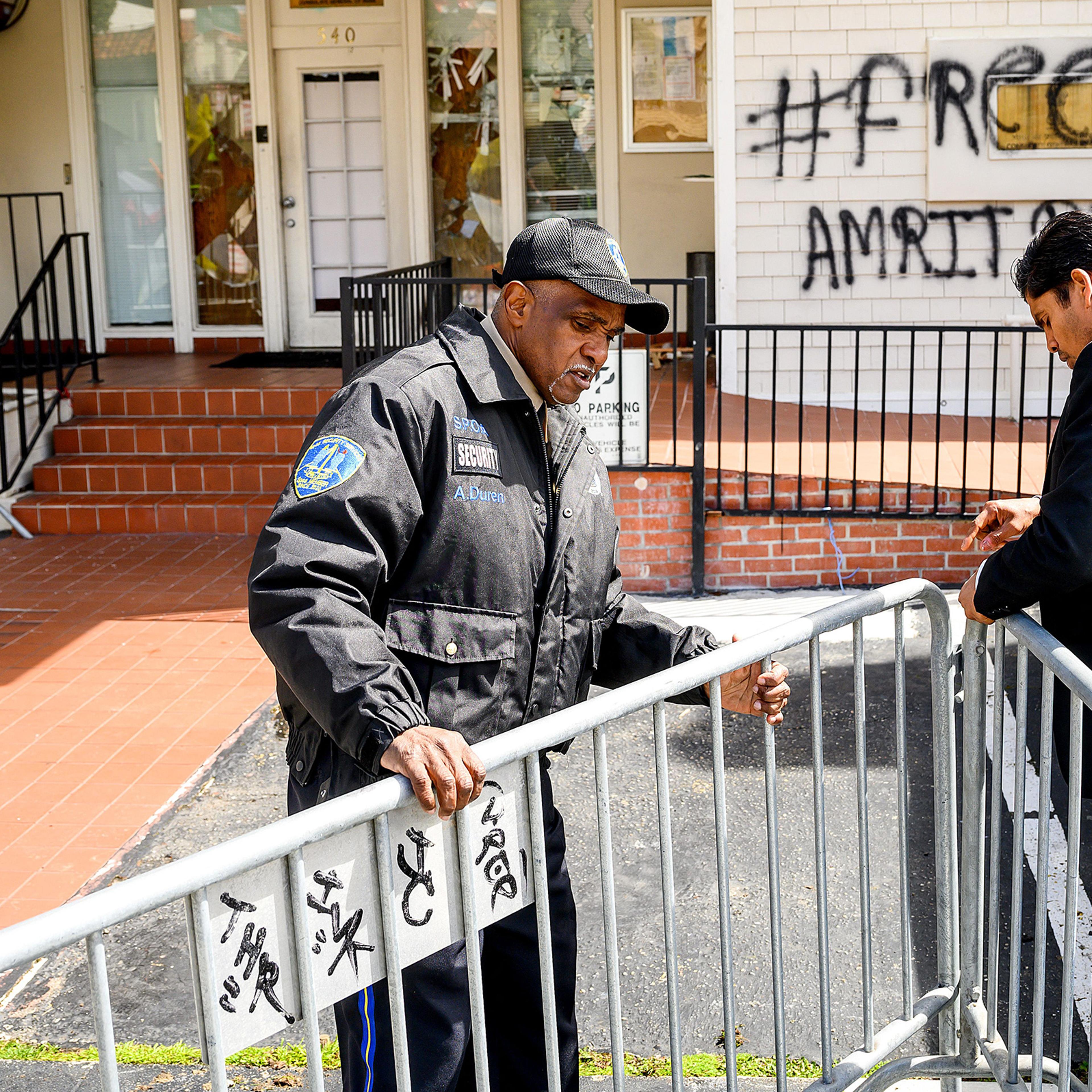 A security guard adjusts barricades at the Indian Consulate as broken windows and a graffitti reading "FreeAmritpal" are seen behind, in San Francisco, Calif. on March 20. Indian authorities extended a mobile internet blackout across a state of about 30 million people on Monday as police hunted a radical Sikh preacher. The blackout extension came after supporters of Amritpal Singh were filmed vandalising India's consulate in San Francisco.