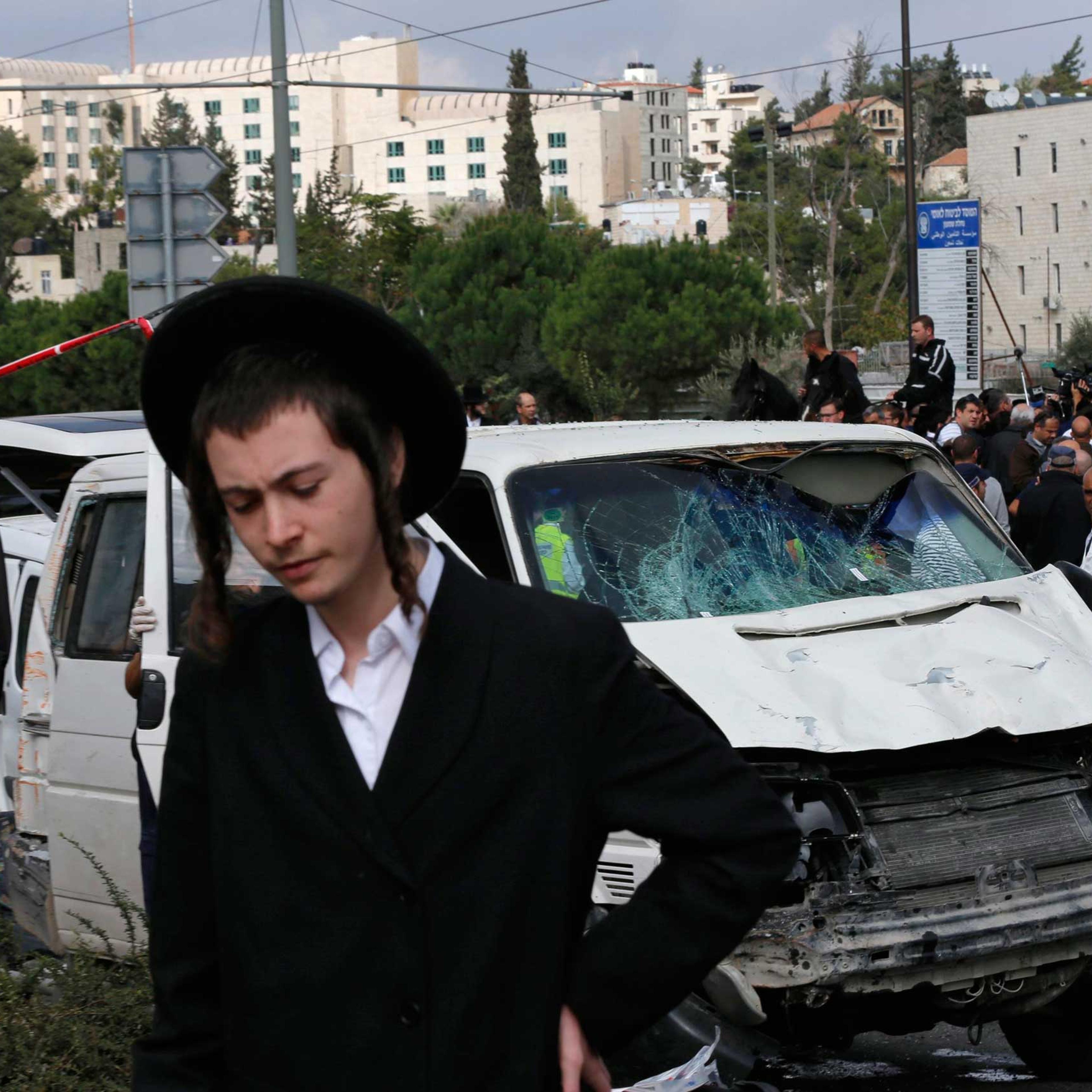 An ultra-Orthodox youth stands in front of the vehicle of a Palestinian motorist who rammed into pedestrians at the scene of an attack in Jerusalem, Nov. 5, 2014.
