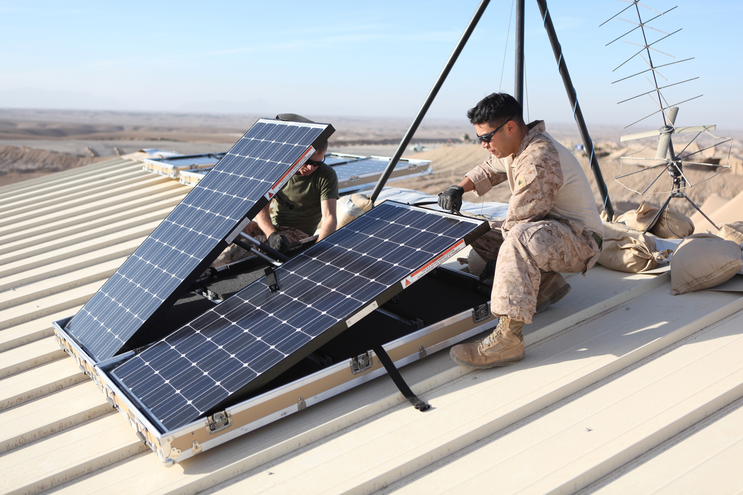 U.S. Marine Corps Corporal Robert G. Sutton (L) and Corporal Moses E. Perez install new solar panels on Combat Outpost Shukvani, Helmand province, Afghanistan, on Nov. 19, 2012