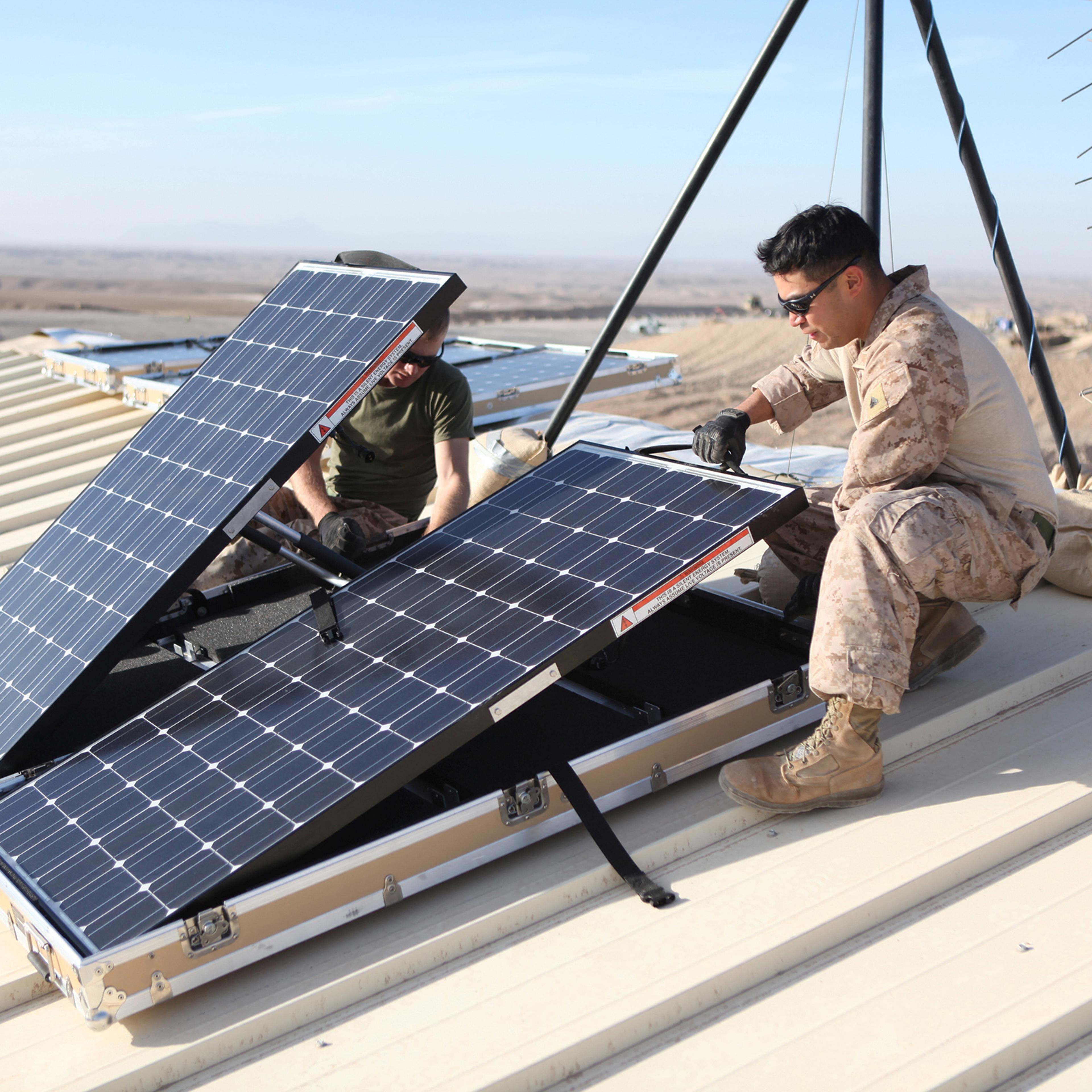U.S. Marine Corps Corporal Robert G. Sutton (L) and Corporal Moses E. Perez install new solar panels on Combat Outpost Shukvani, Helmand province, Afghanistan, on Nov. 19, 2012