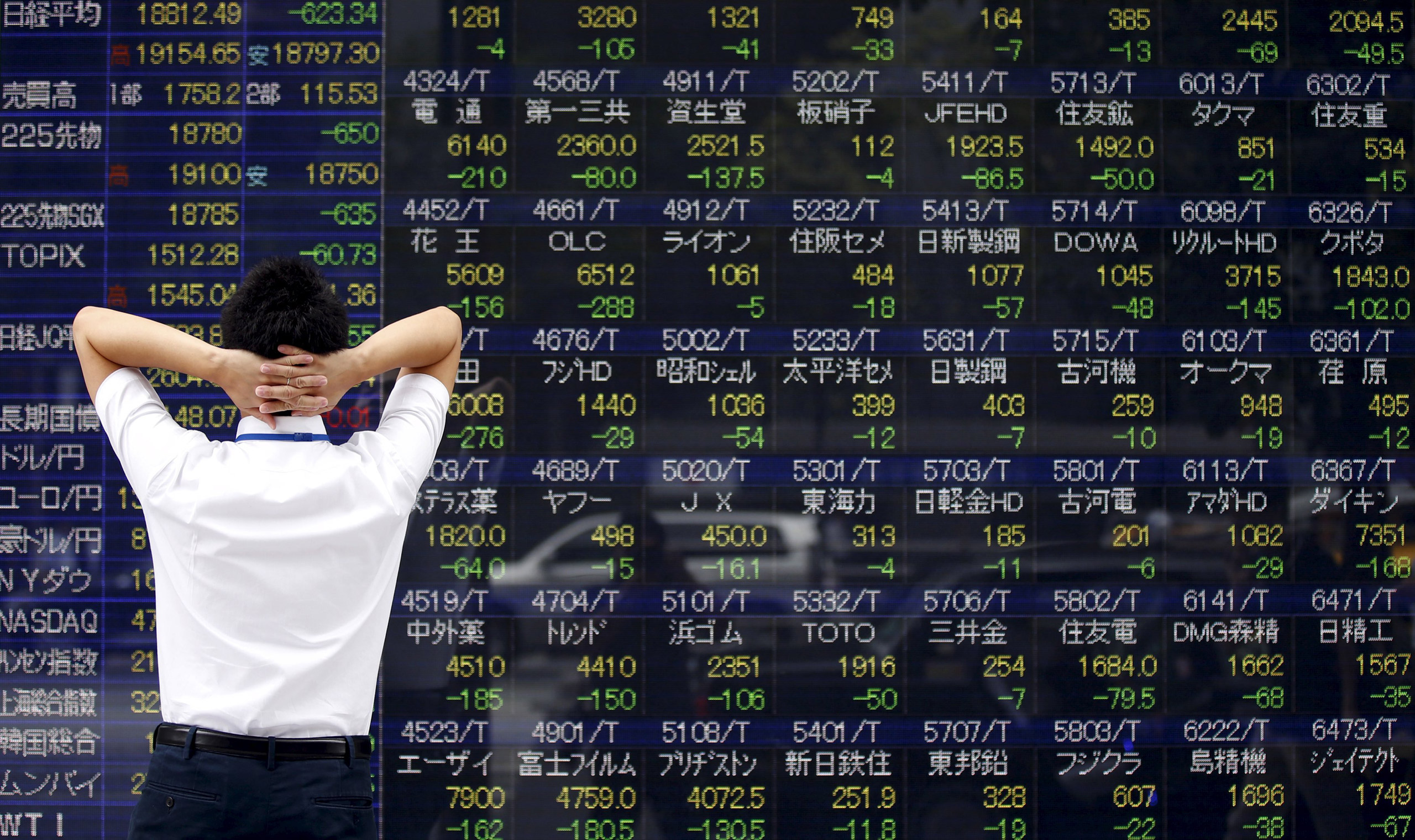 A man looks at a stock quotation board outside a brokerage in Tokyo, August 24, 2015. Asian stocks dived to 3-year lows on Monday as a rout in Chinese equities gathered pace, hastening an exodus from riskier assets as fears of a China-led global economic