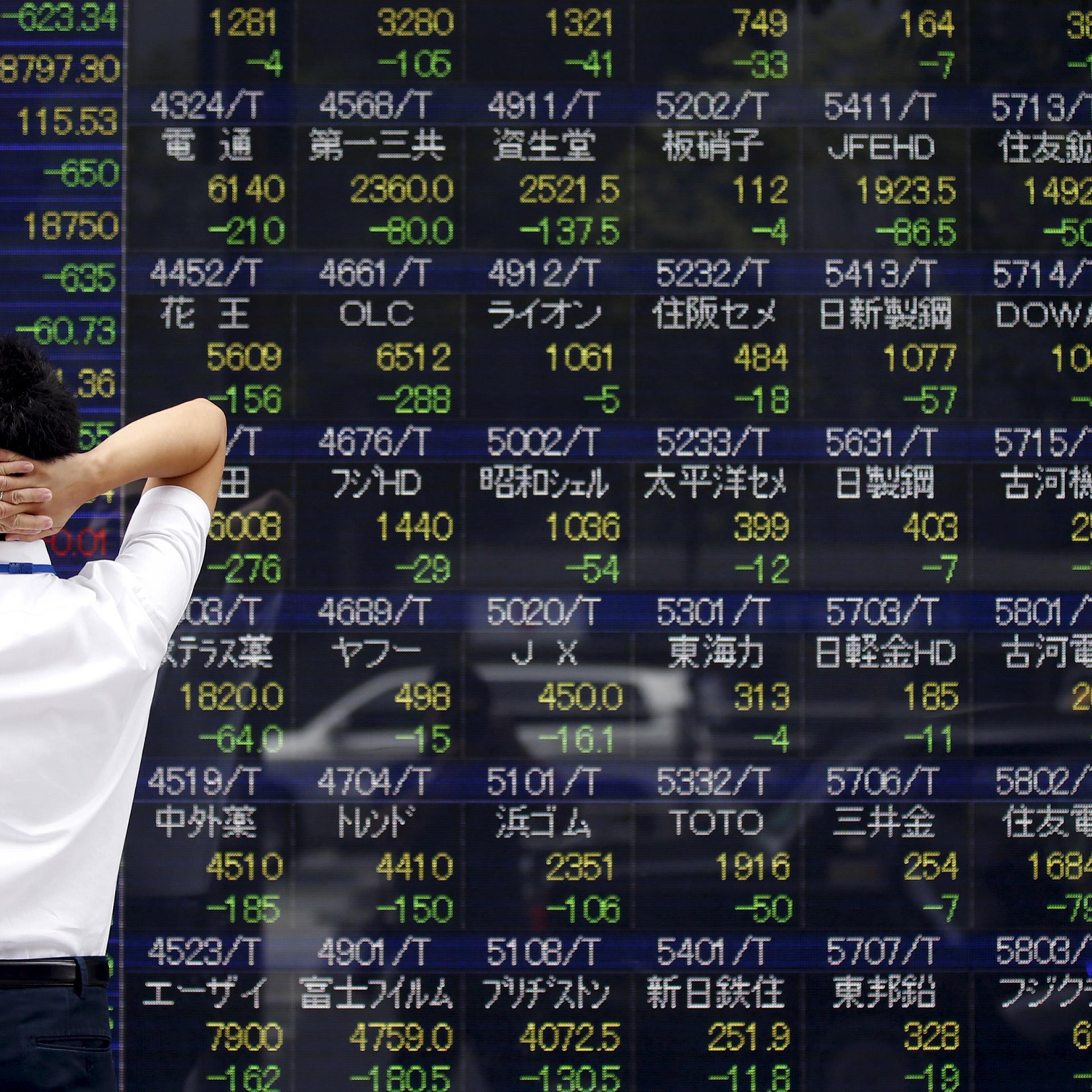 A man looks at a stock quotation board outside a brokerage in Tokyo, August 24, 2015. Asian stocks dived to 3-year lows on Monday as a rout in Chinese equities gathered pace, hastening an exodus from riskier assets as fears of a China-led global economic