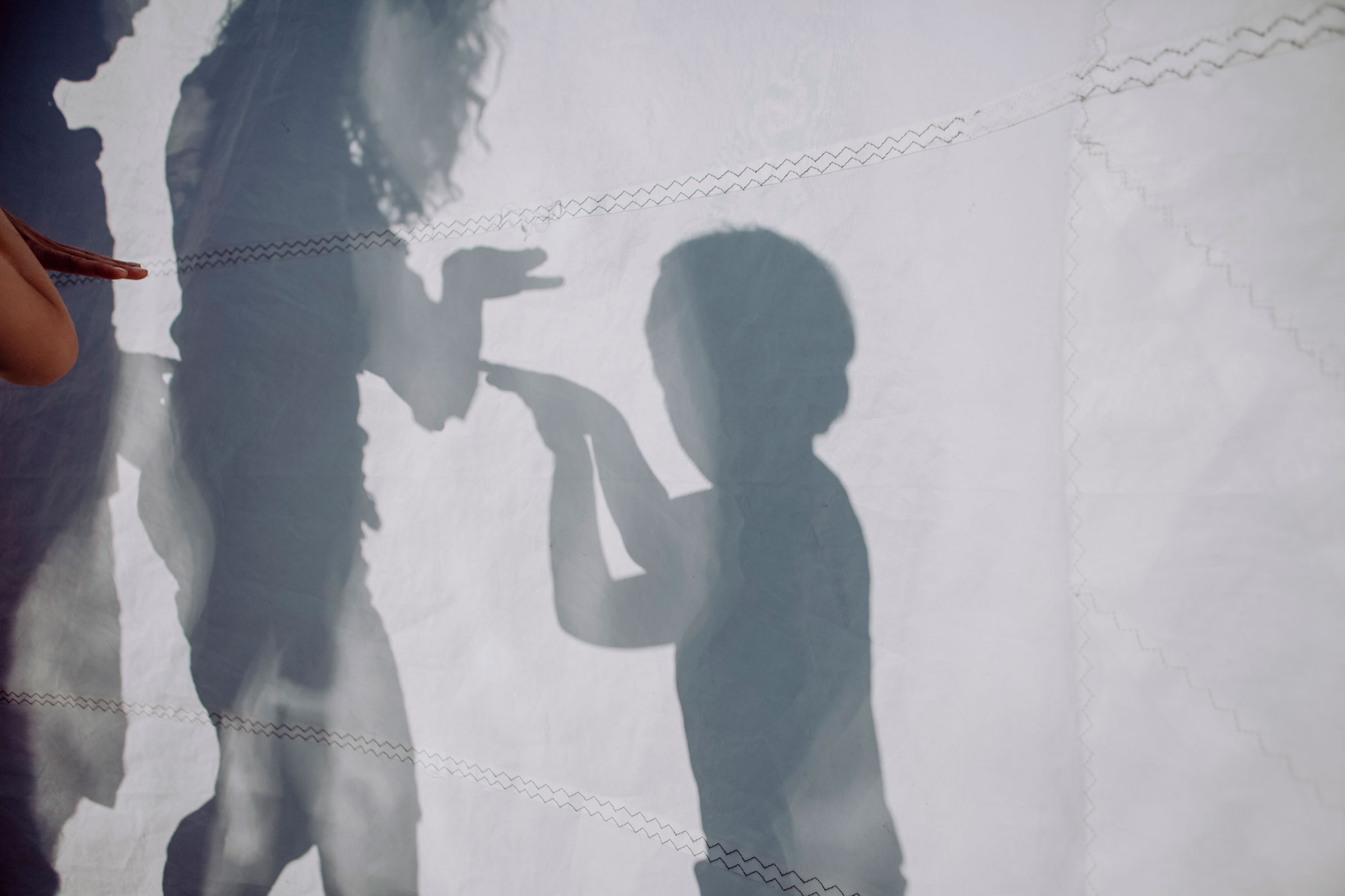 Family doing a shadow play behind sail