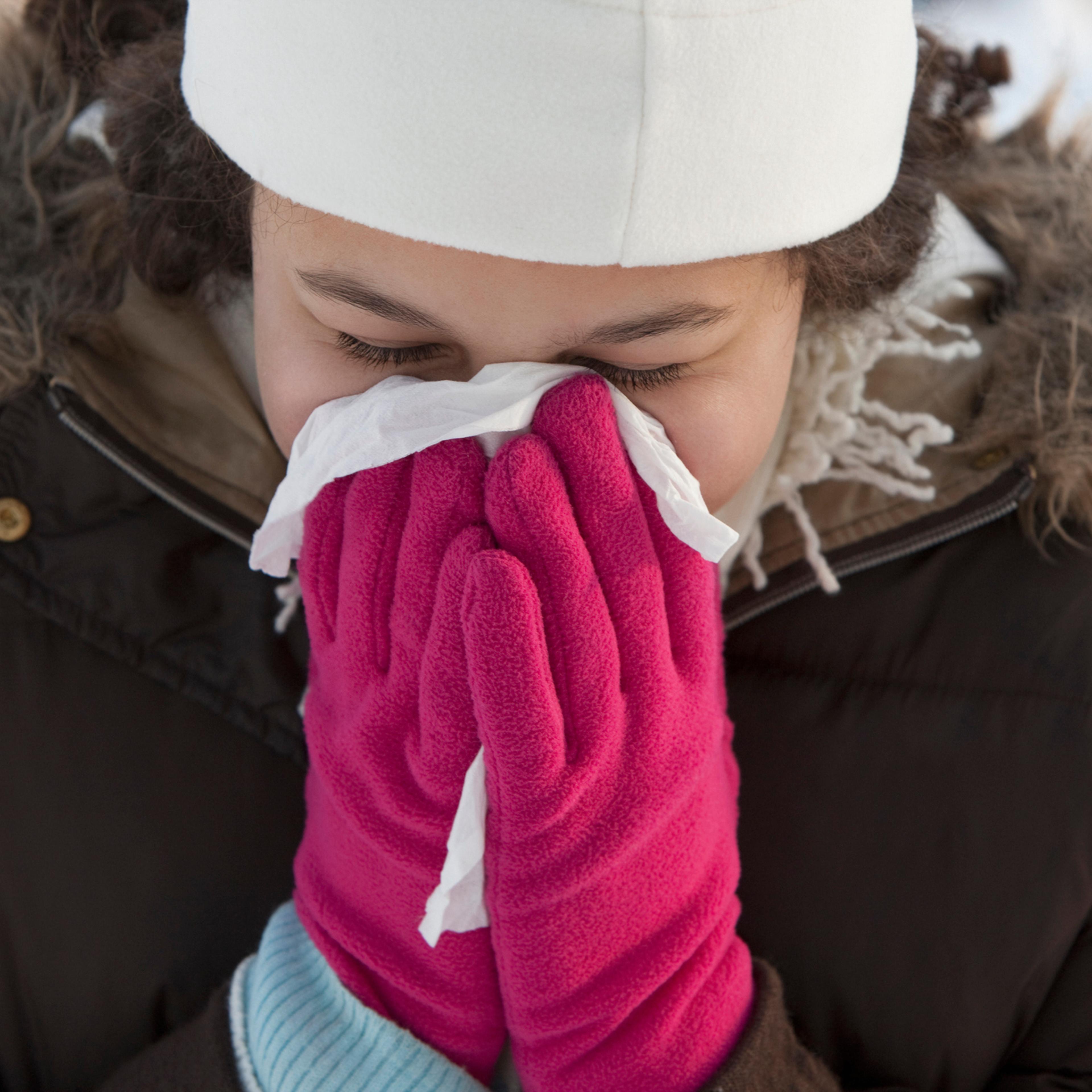 Woman blowing her nose outdoors in winter