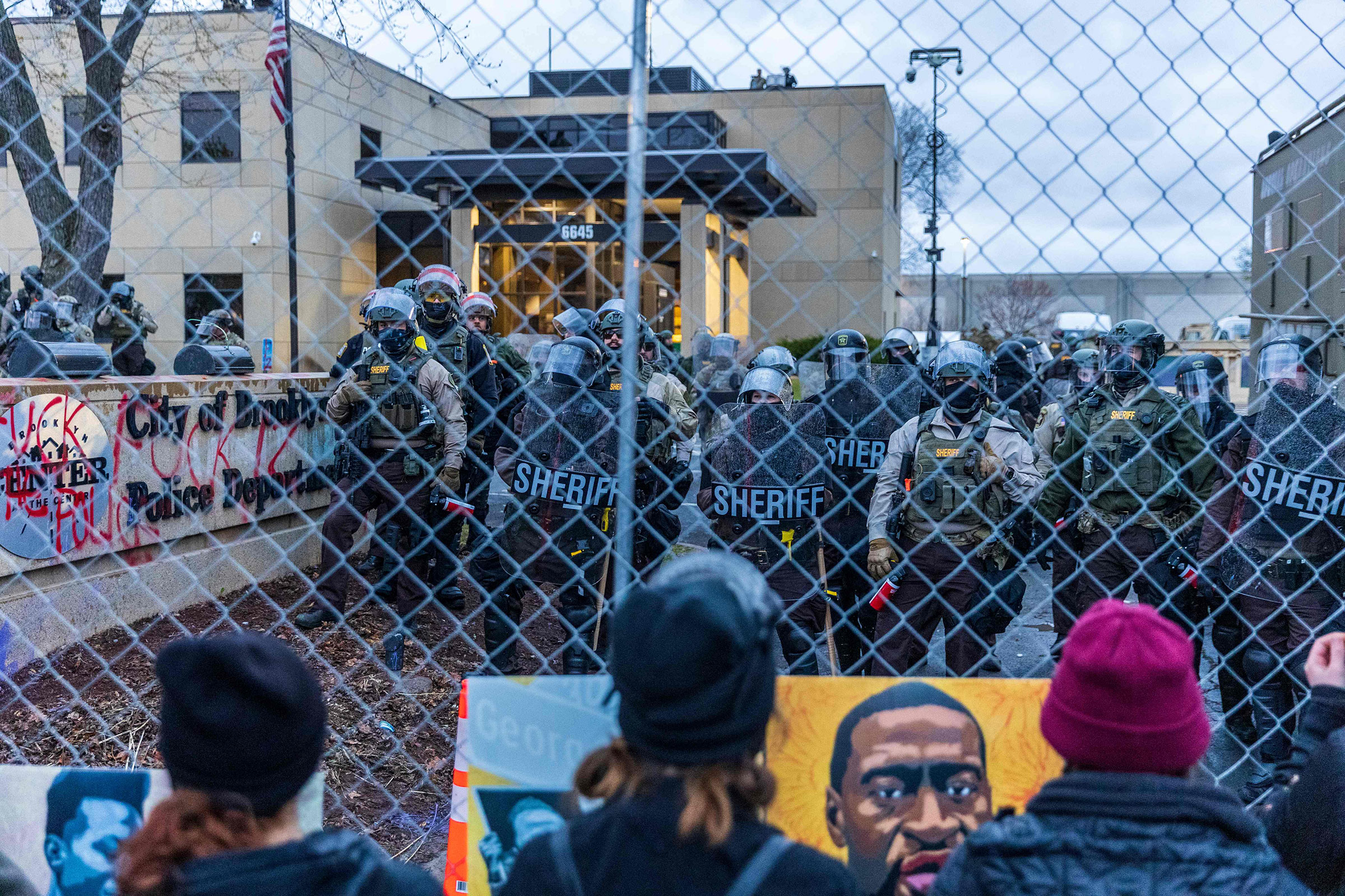 Sheriff officers stand guard outside the Brooklyn Center police station as demonstrators stand on the other side of the chain-link fence protesting the death of Daunte Wright who was shot and killed by a police officer in Brooklyn Center, Minn. on April 