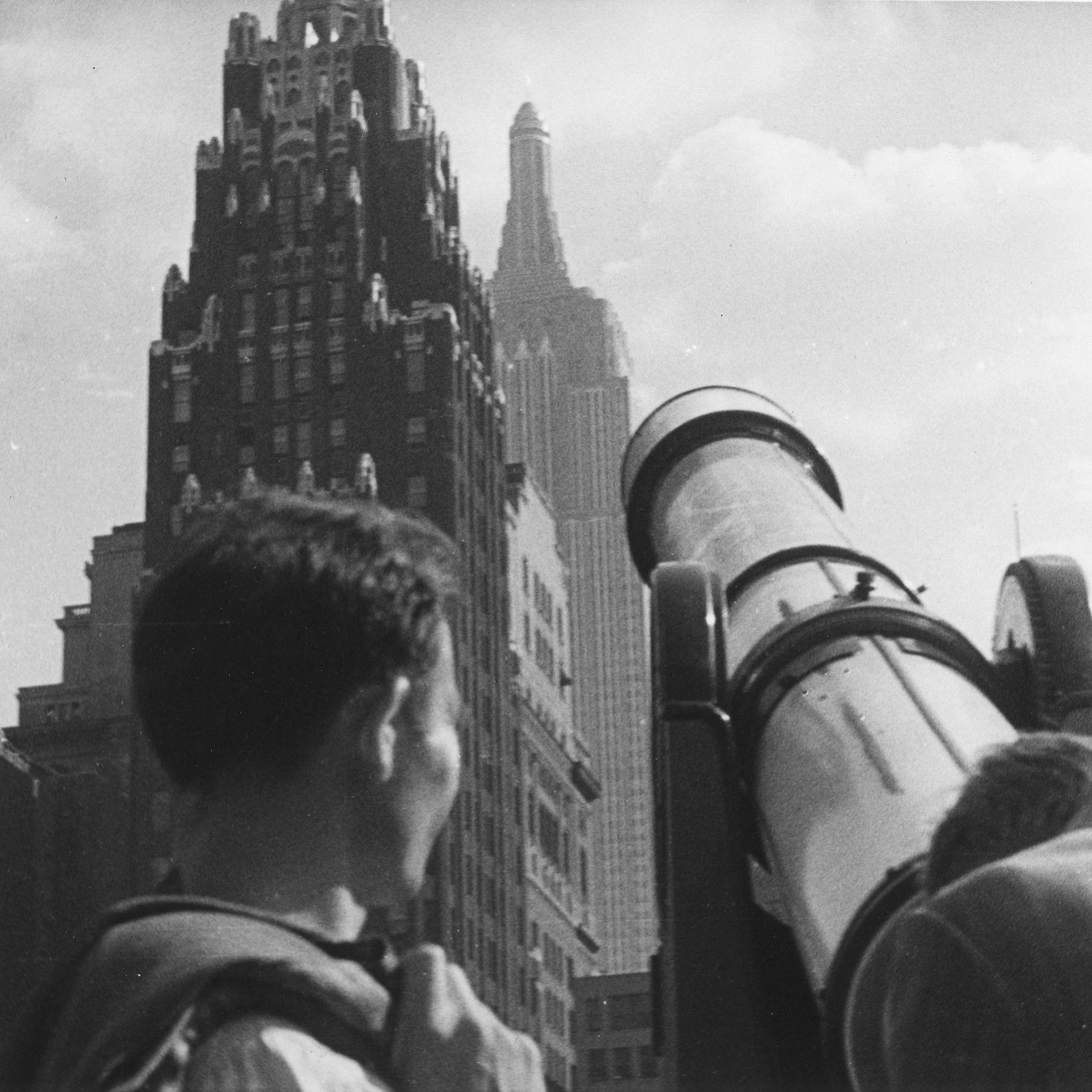 Tourists at Bryant Park looking through a telescope towards American Radiator Building and the Empire State Building, New York City, 1929.