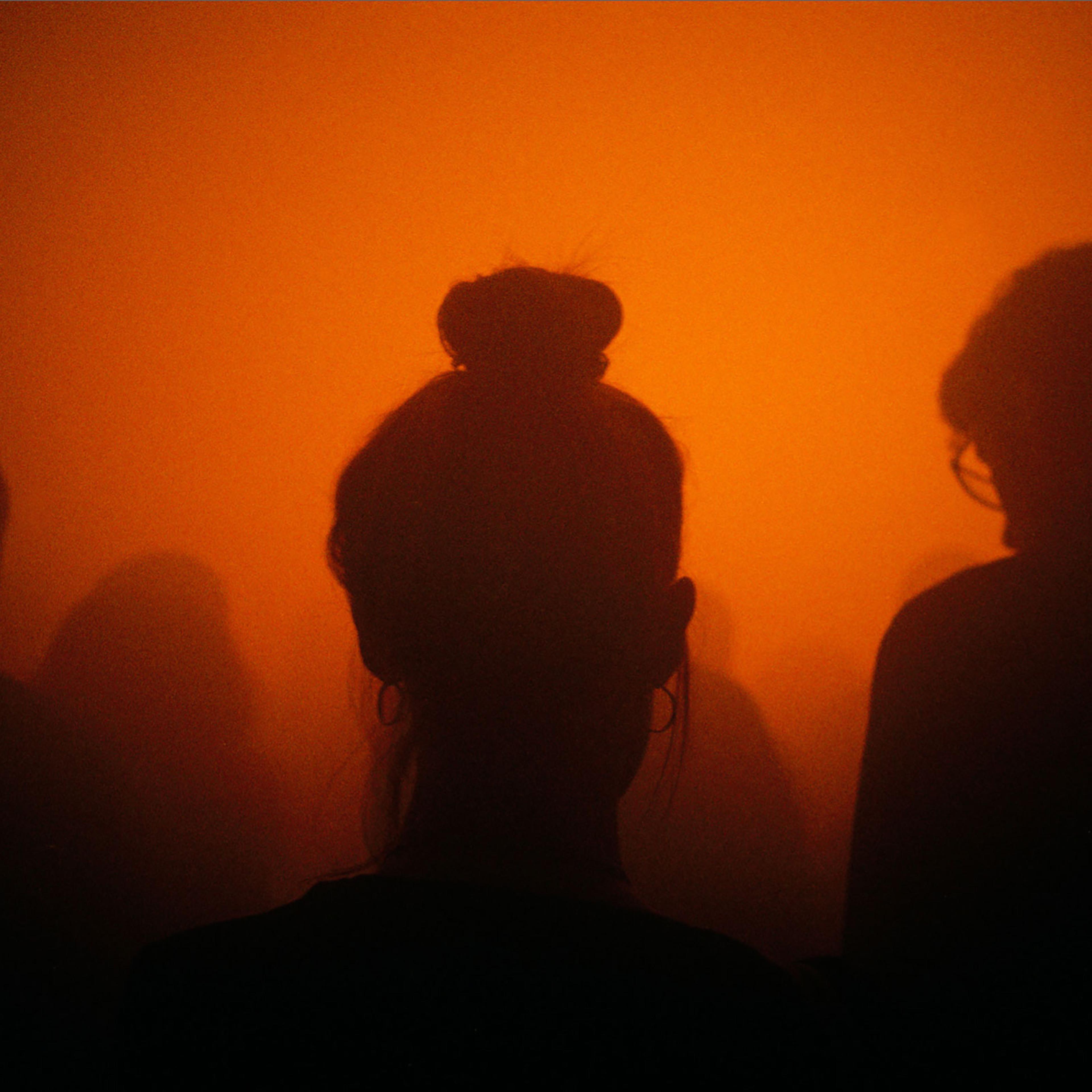 Silhouette of young women in a crowd with smokey orange light