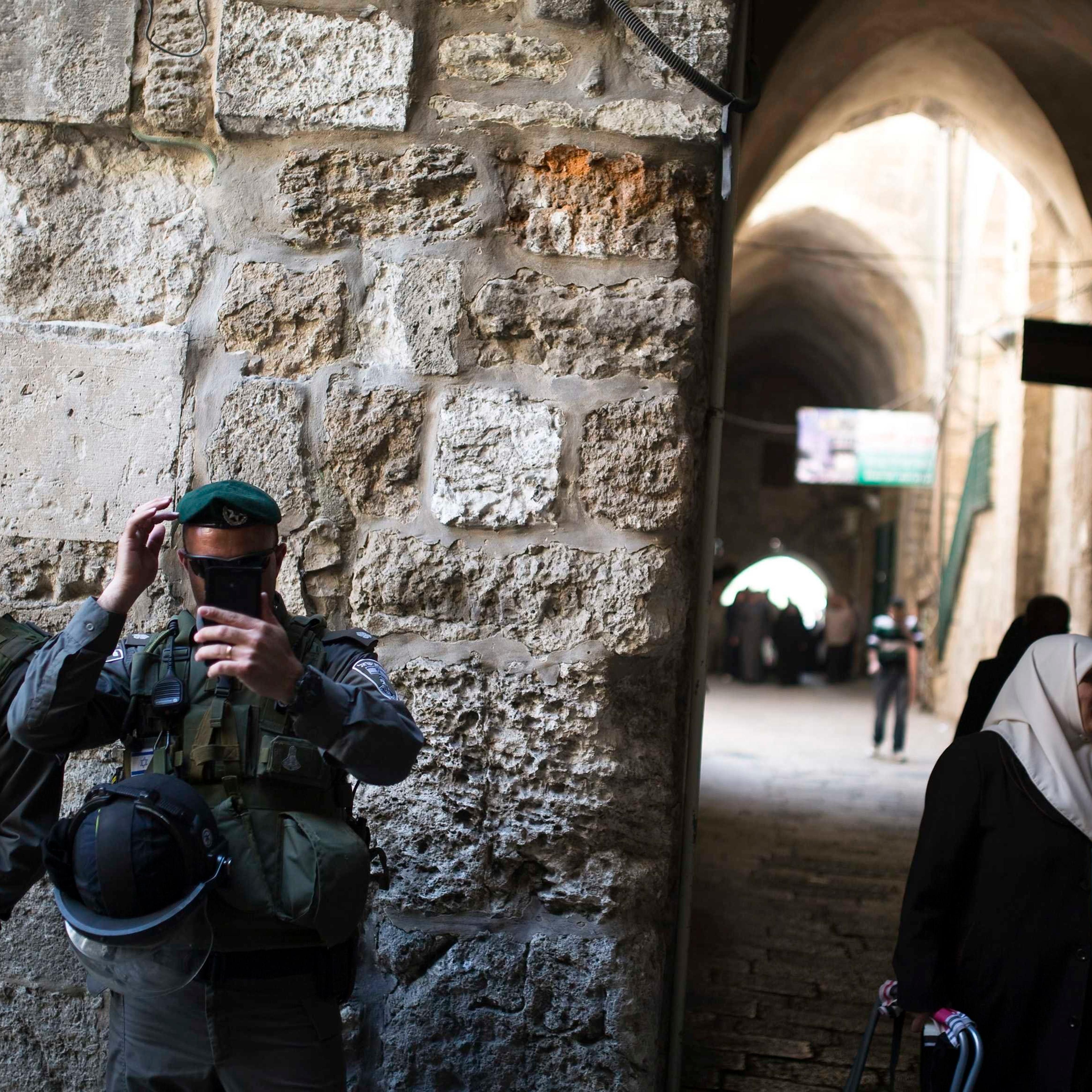 Palestinian women walk near Israeli border policemen after Friday prayers in Jerusalem's Old City