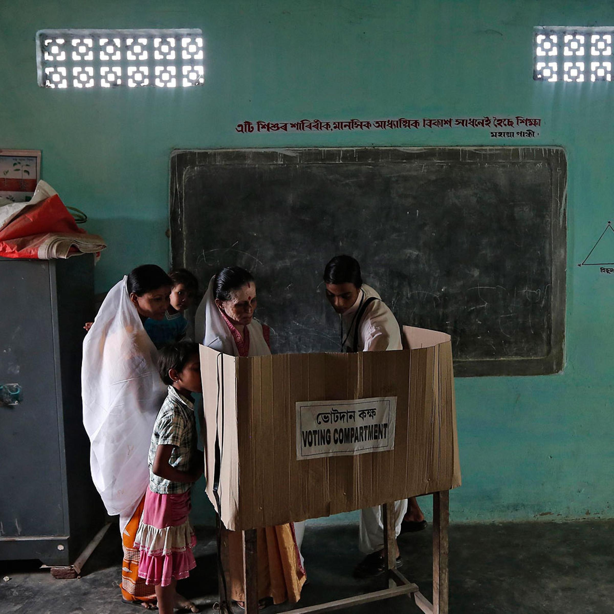 A polling officer helps a woman to cast her vote at a polling station in Majuli, a large river island in the Brahmaputra river, Jorhat district, in the northeastern Indian state of Assam, April 7, 2014.