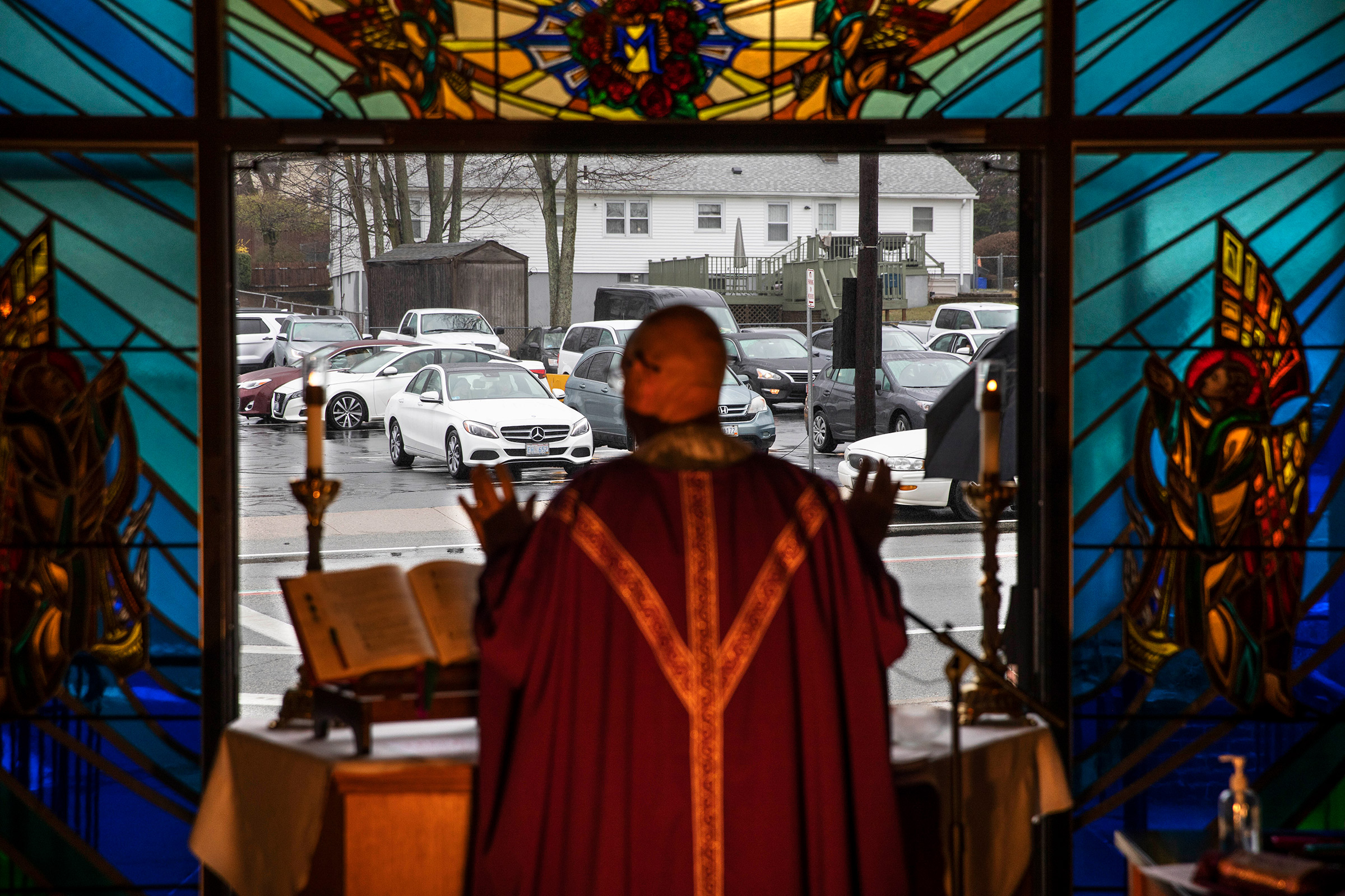 Rev. Peter Gower celebrates Mass from the front door of Our Lady of Grace Catholic Church as worshippers listen over the radio from their cars in the parking lot, Sunday, March 29, in Johnston, R.I. 