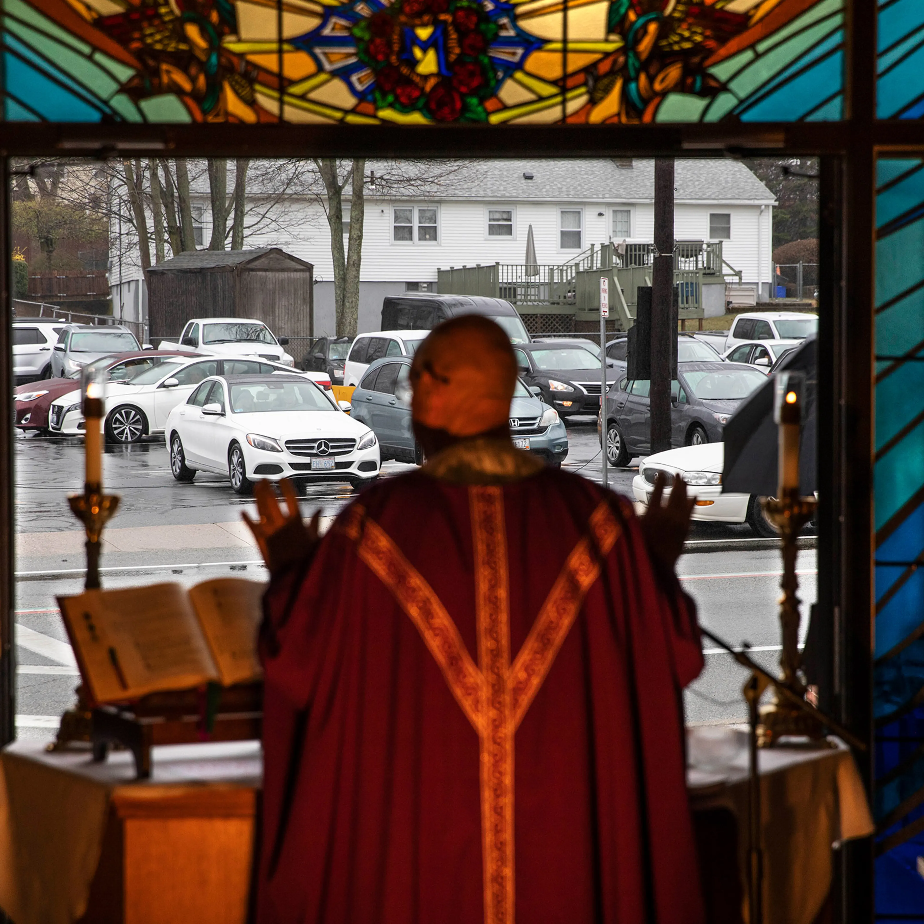 Rev. Peter Gower celebrates Mass from the front door of Our Lady of Grace Catholic Church as worshippers listen over the radio from their cars in the parking lot, Sunday, March 29, in Johnston, R.I.