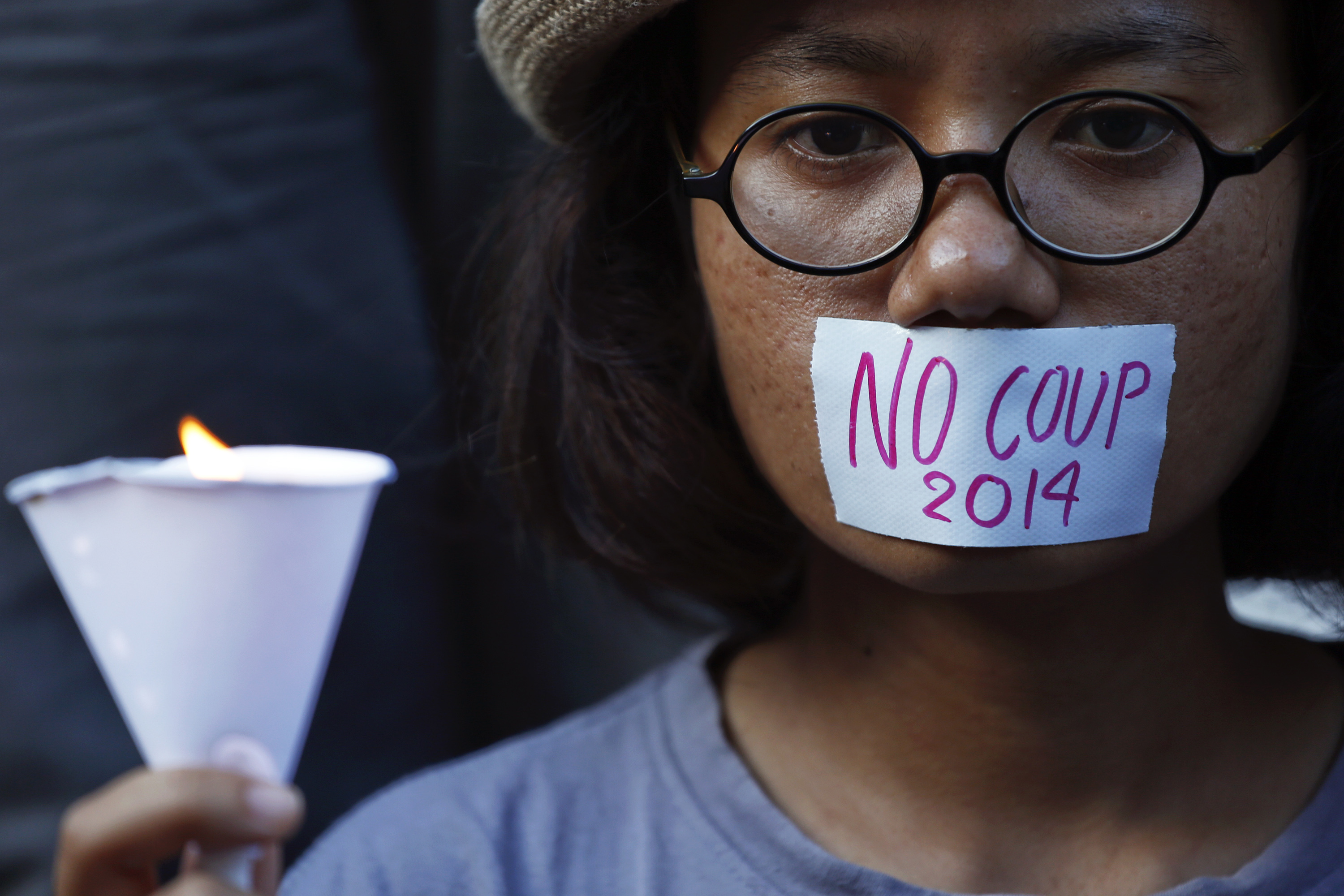 A girl holds a candle during a protest against military rule in central Bangkok