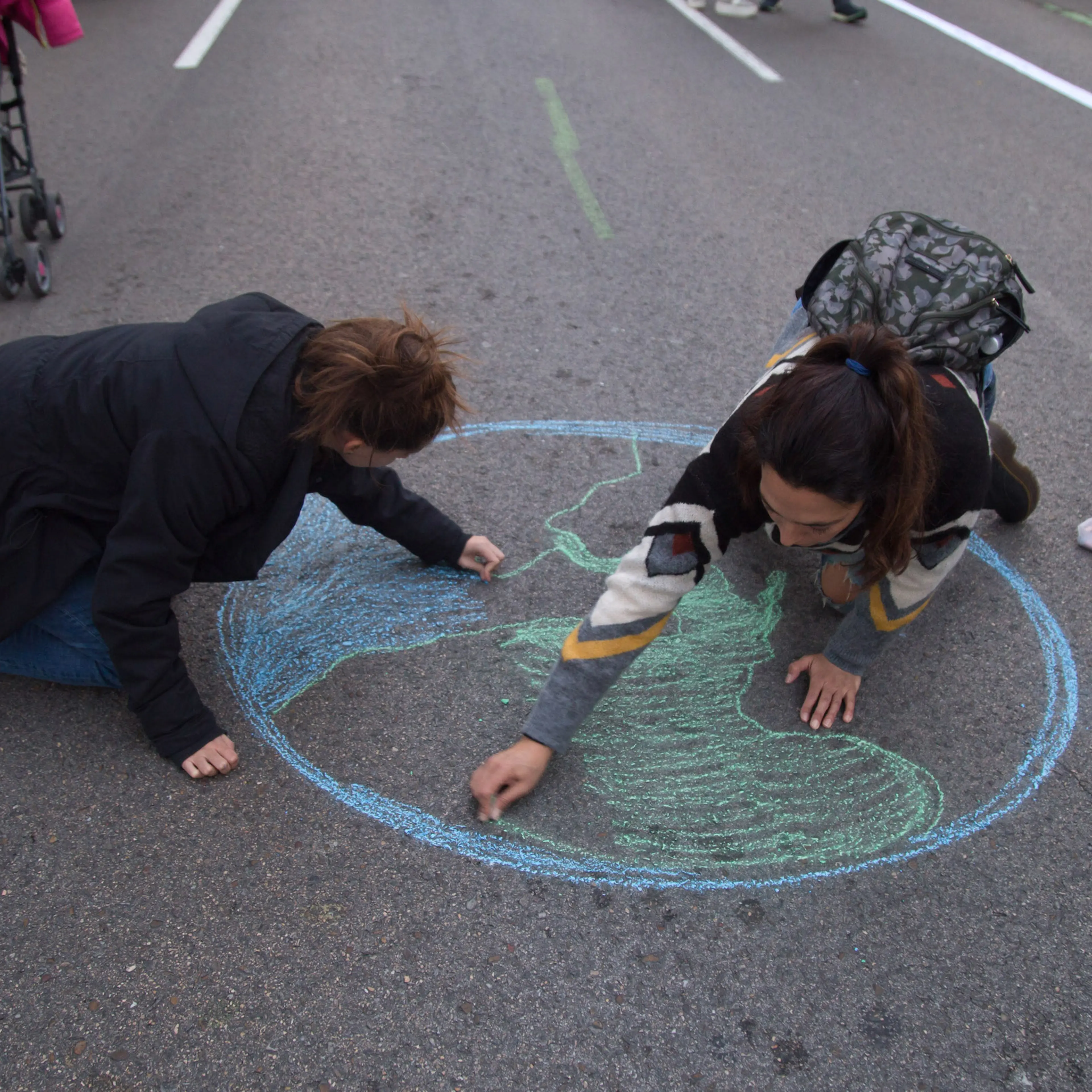 Activists draw the planet earth on the ground during the
