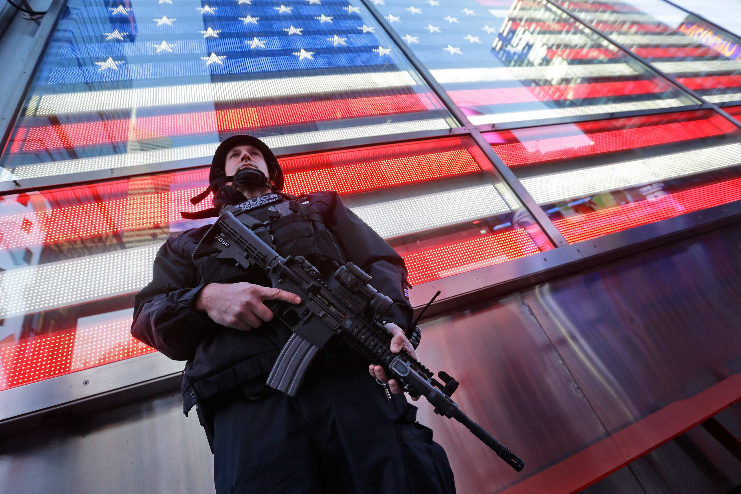 A heavily armed New York city police officer with the Strategic Response Group stands guard at the armed forces recruiting center in New York's Times Square, Saturday, Nov. 14, 2015. Police in New York say they've deployed extra units to crowded areas of