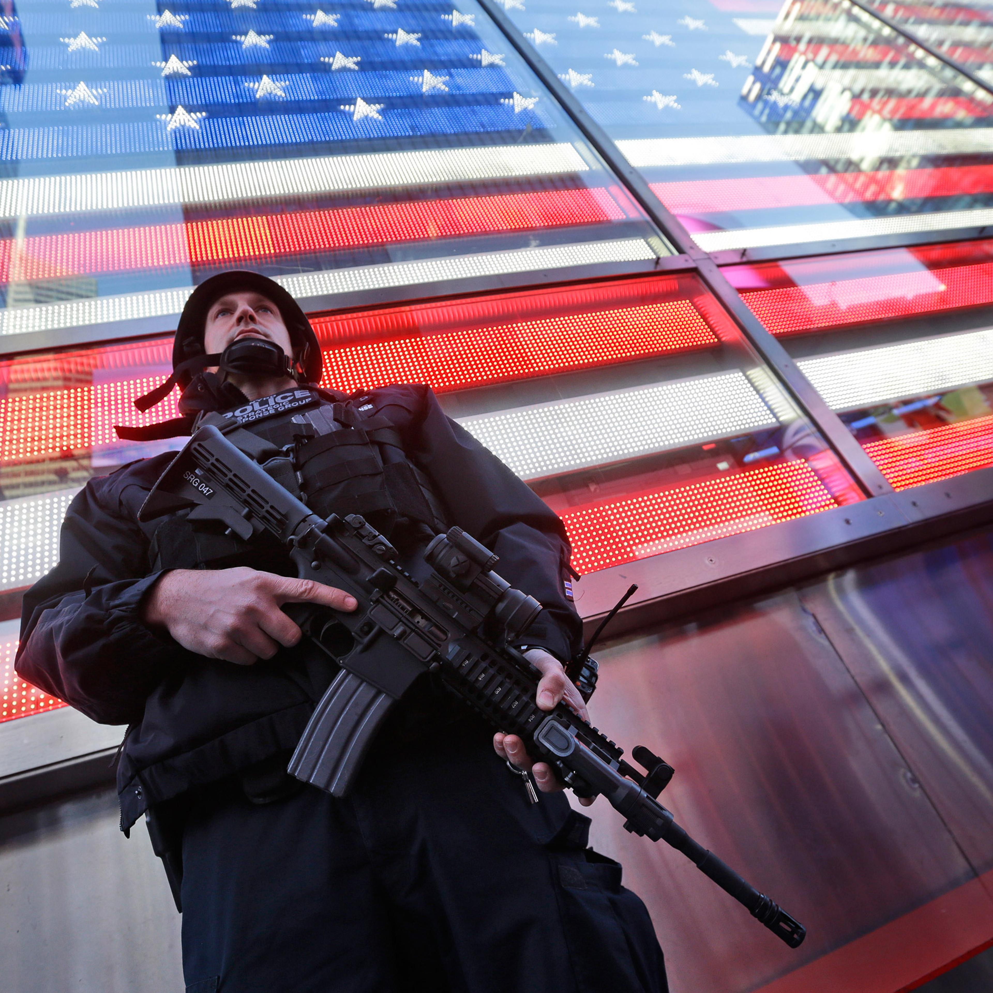 A heavily armed New York city police officer with the Strategic Response Group stands guard at the armed forces recruiting center in New York's Times Square, Saturday, Nov. 14, 2015. Police in New York say they've deployed extra units to crowded areas of