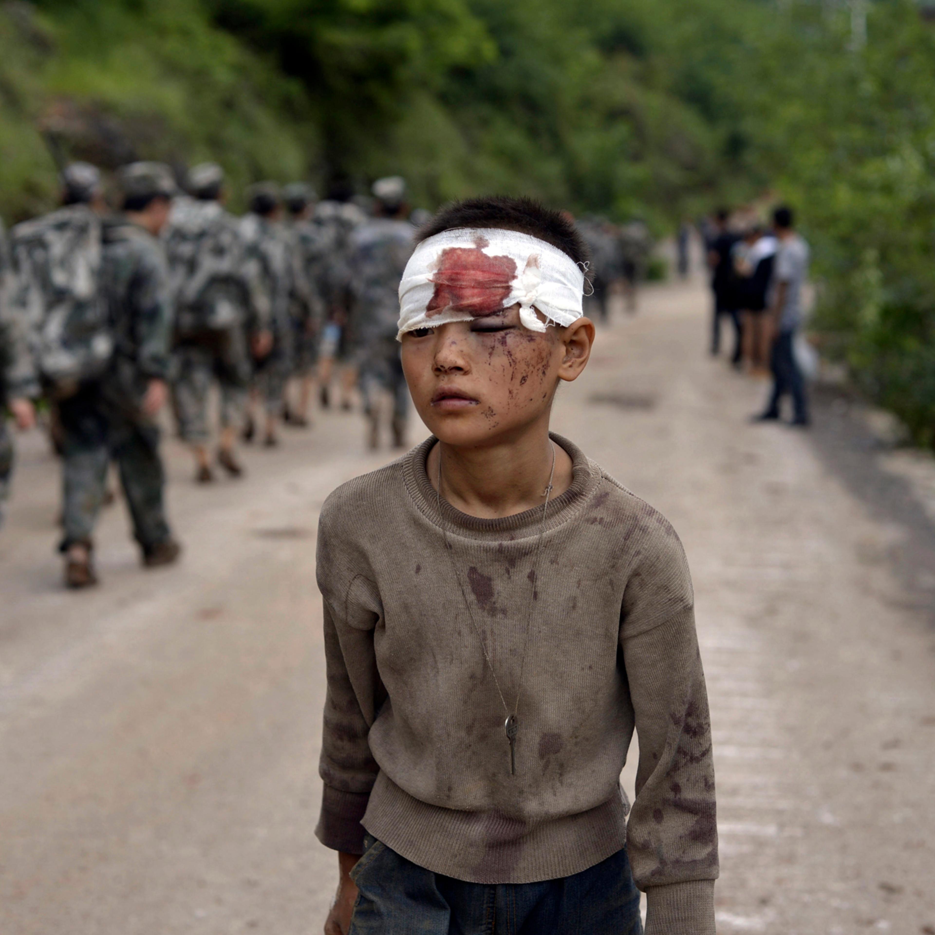An injured child walks past rescuers heading towards the epicenter of an earthquake that struck the town of Longtoushan in Ludian county in southwest China's Yunnan province, Aug. 4, 2014