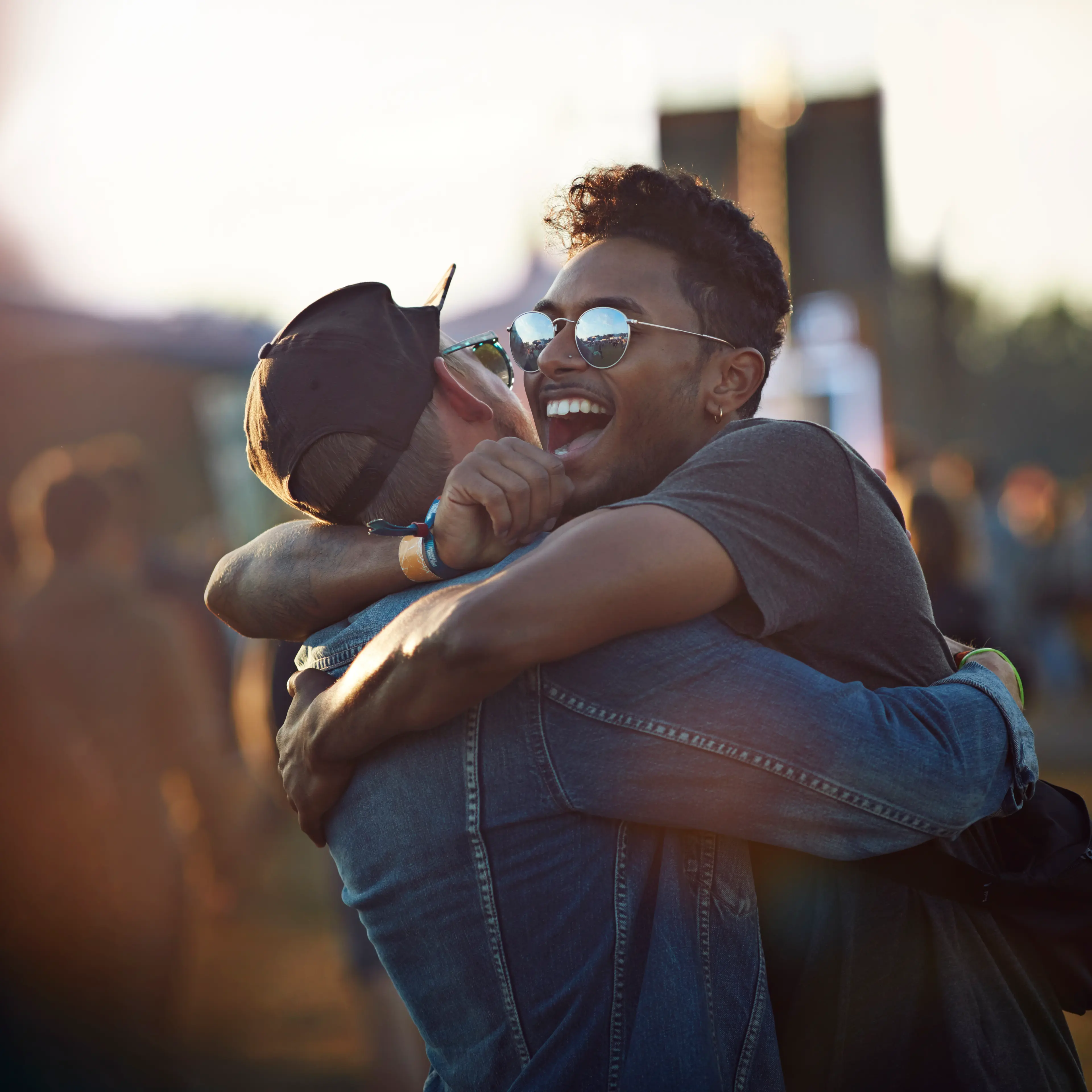 Friends hugging & laughing at big festival