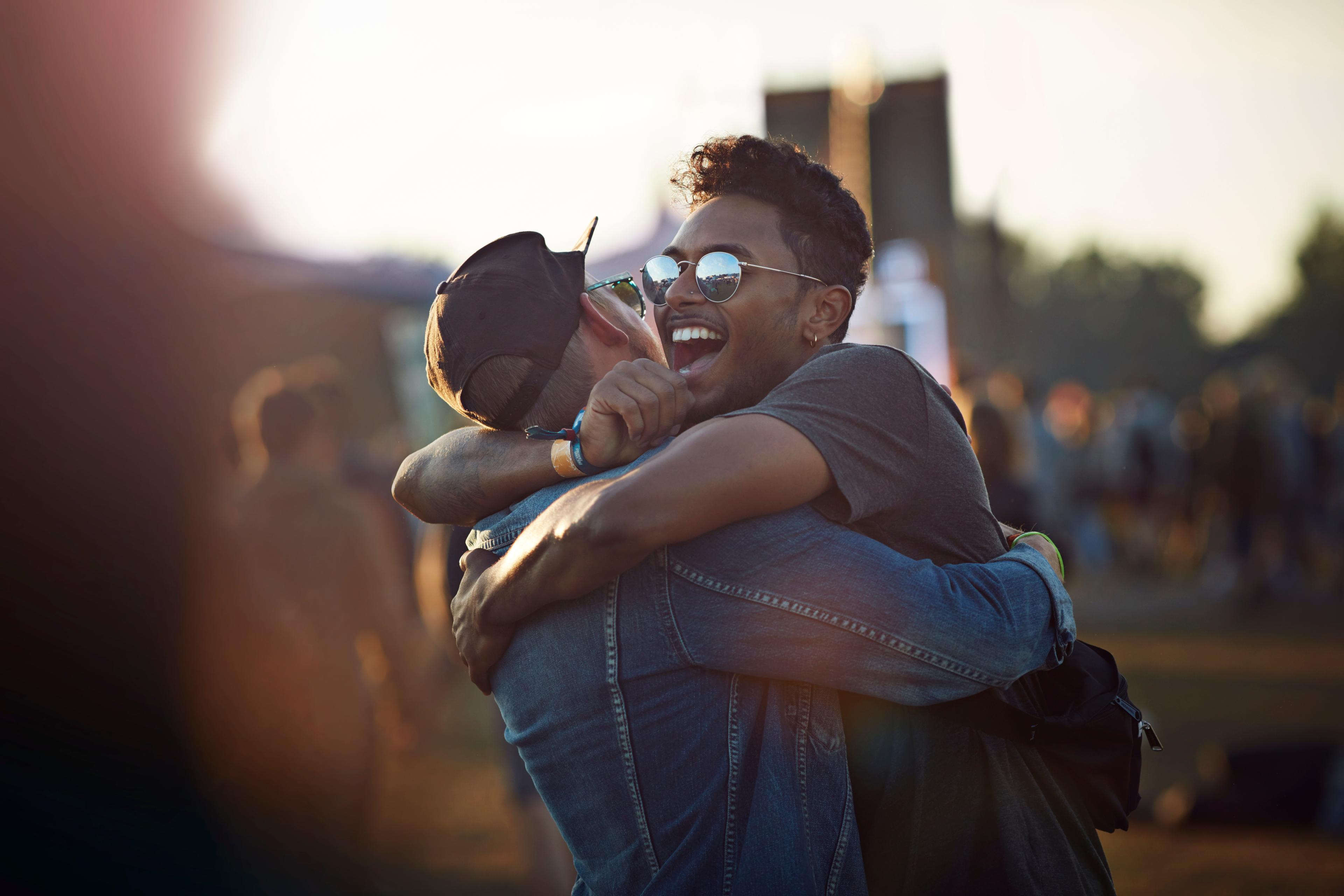 Friends hugging & laughing at big festival